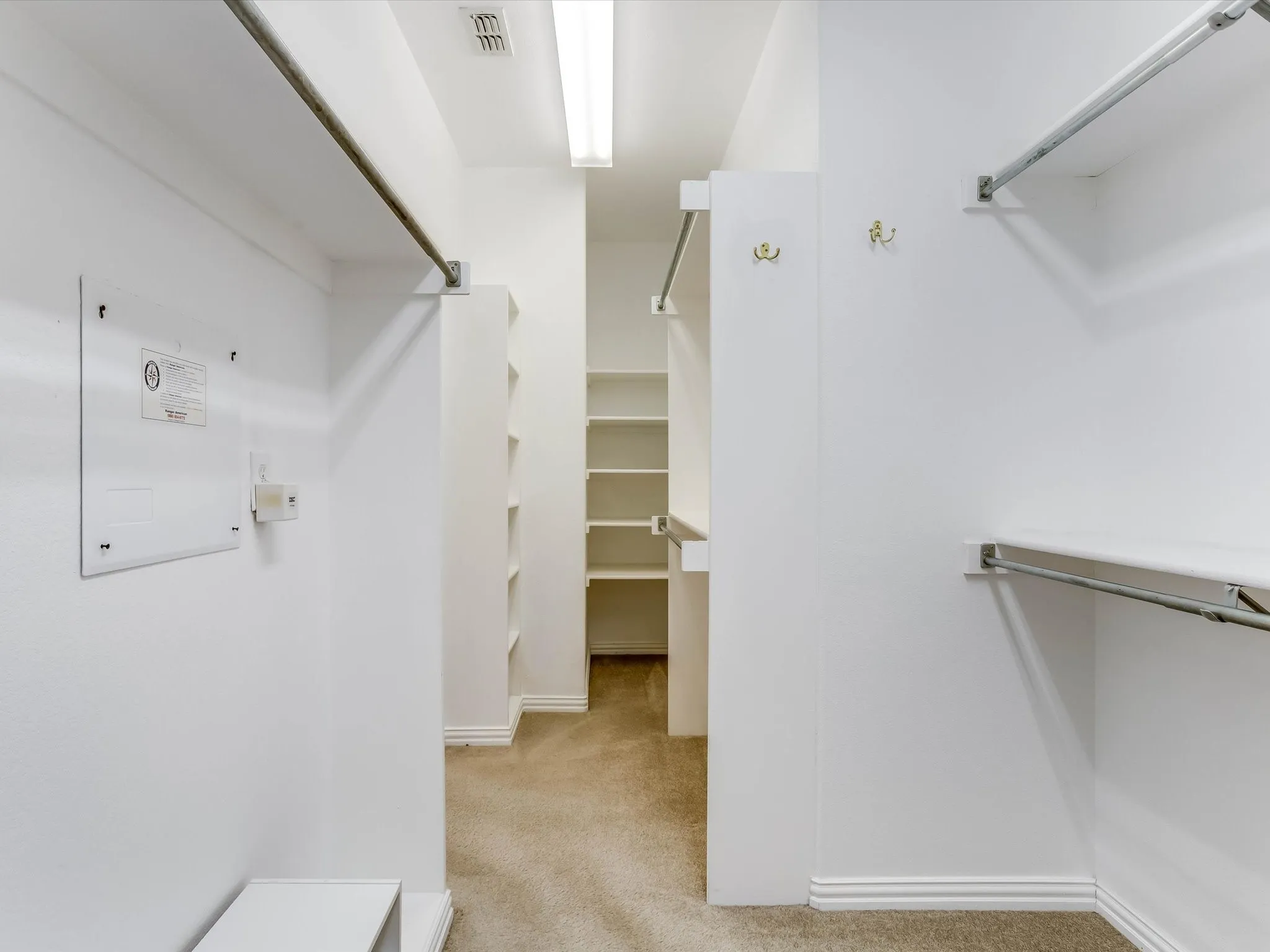 Walk-in closet featuring tiered clothing rods, integrated shelving units, and mounted garment hooks
