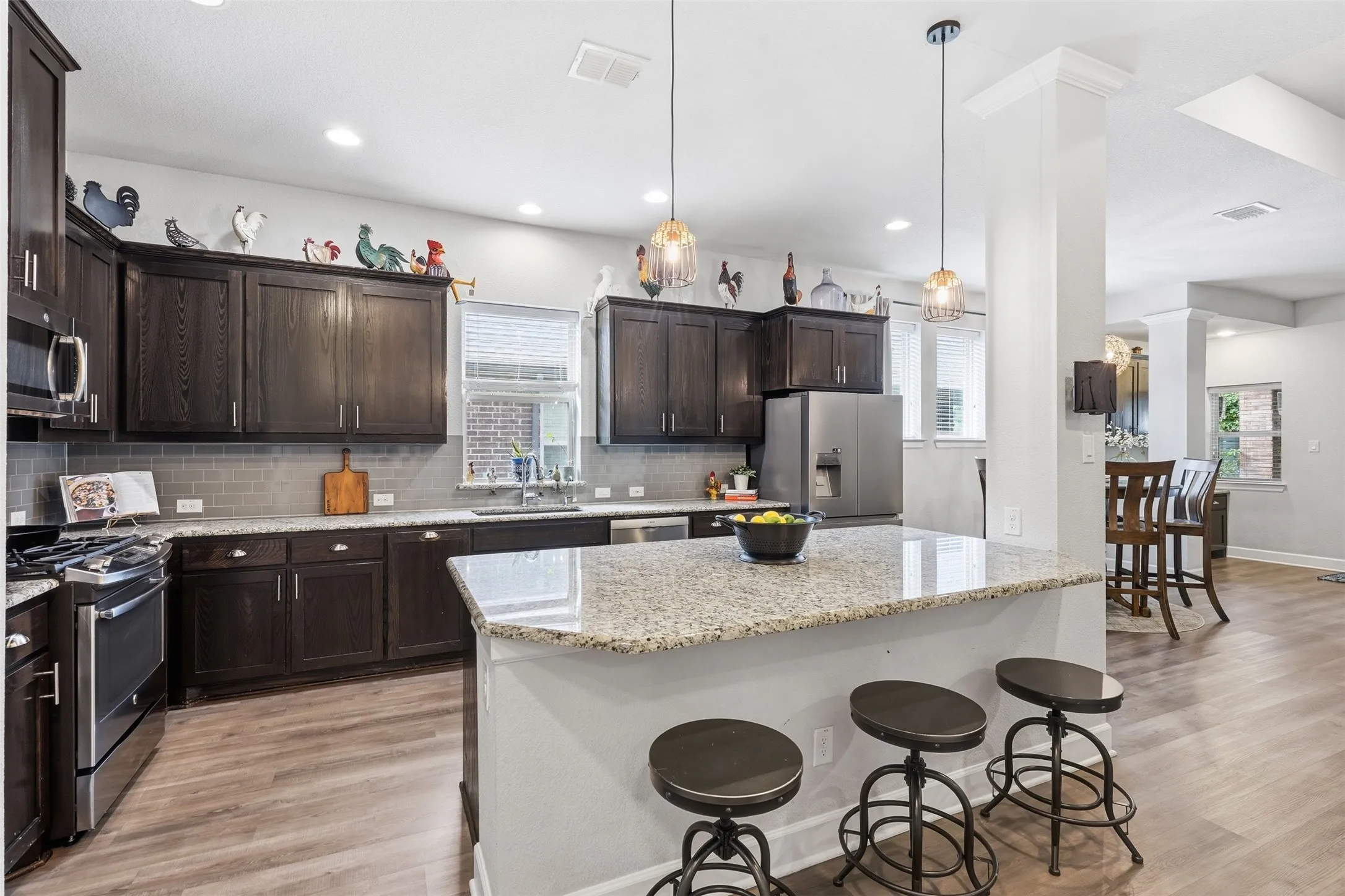 Kitchen featuring dark-finish cabinetry, stone countertops, central island, subway tile backsplash, and stainless-steel appliances