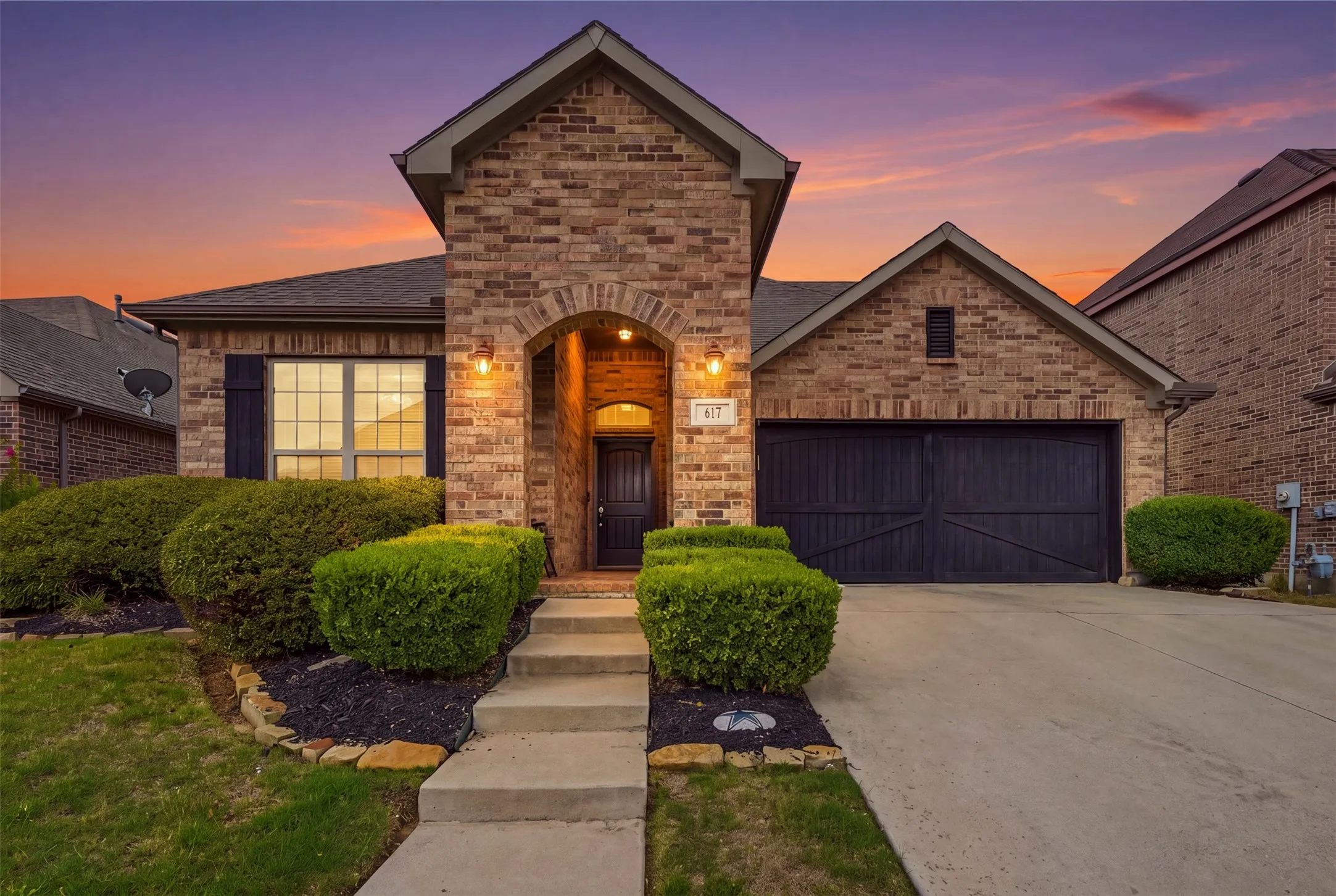 Brick exterior featuring a gabled roofline, covered arched entryway, and dual-pane windows with dark exterior shutters