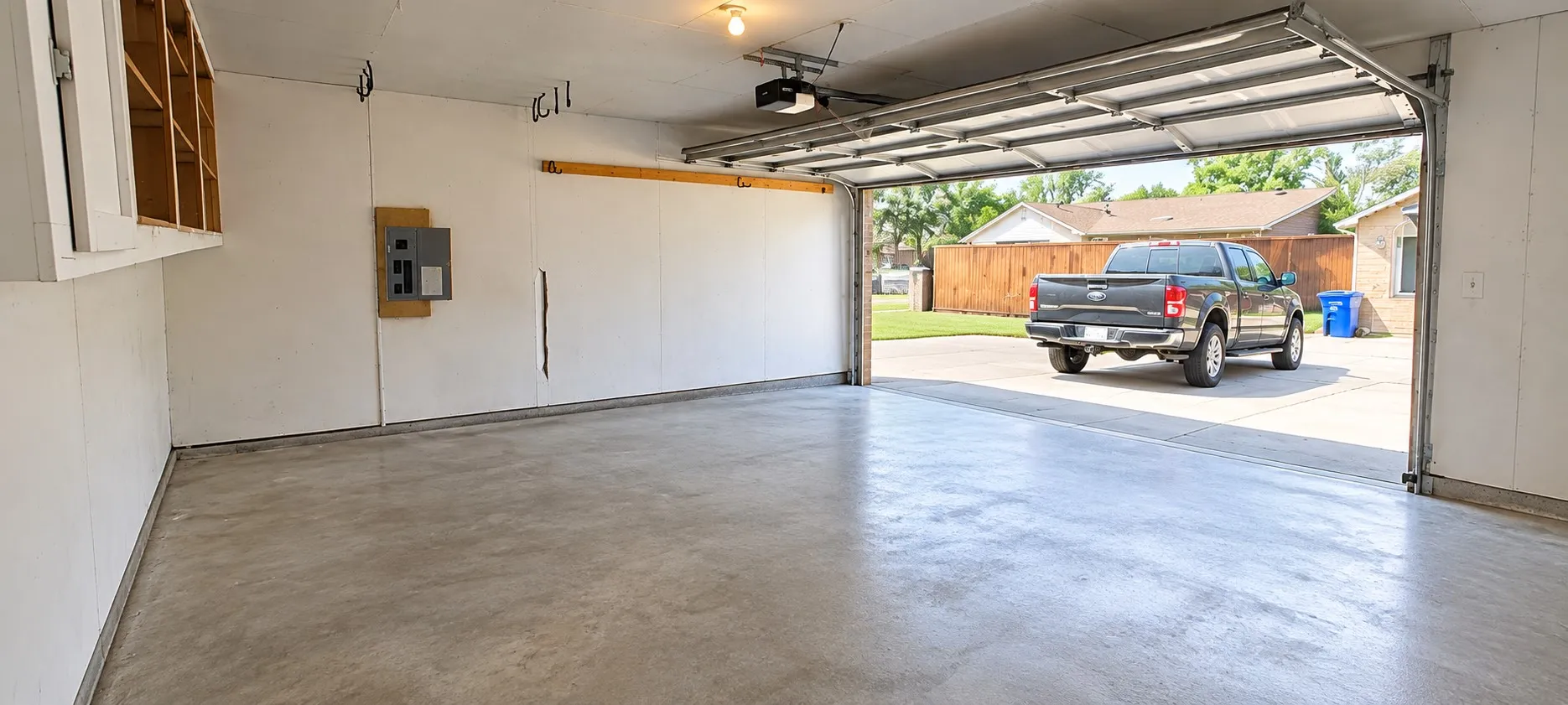 Attached garage featuring a concrete floor, motorized sectional garage door, built-in upper wall cabinetry, and electrical panel