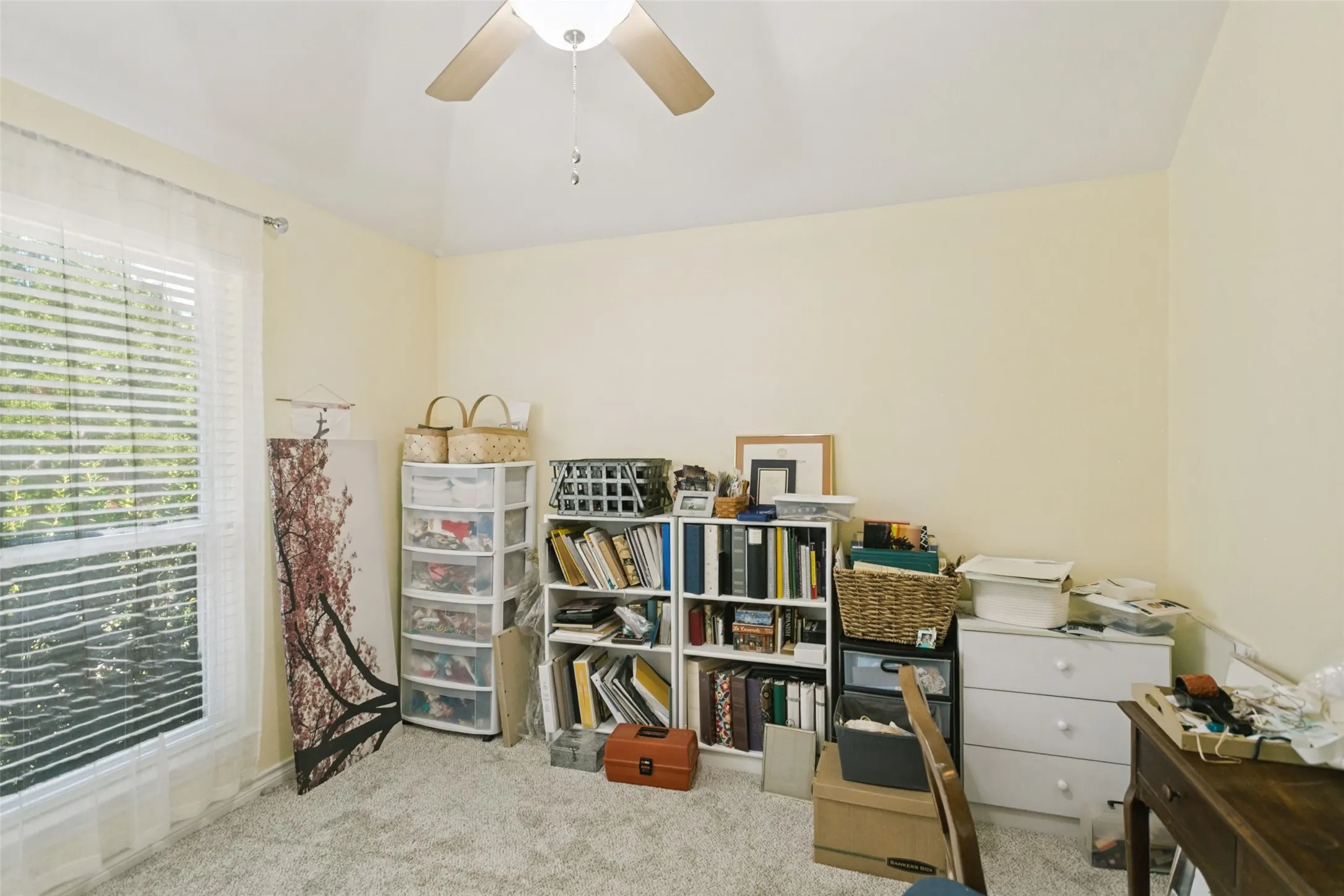 Vaulted ceiling featuring a central ceiling fan with integrated lighting and a large window with horizontal blinds