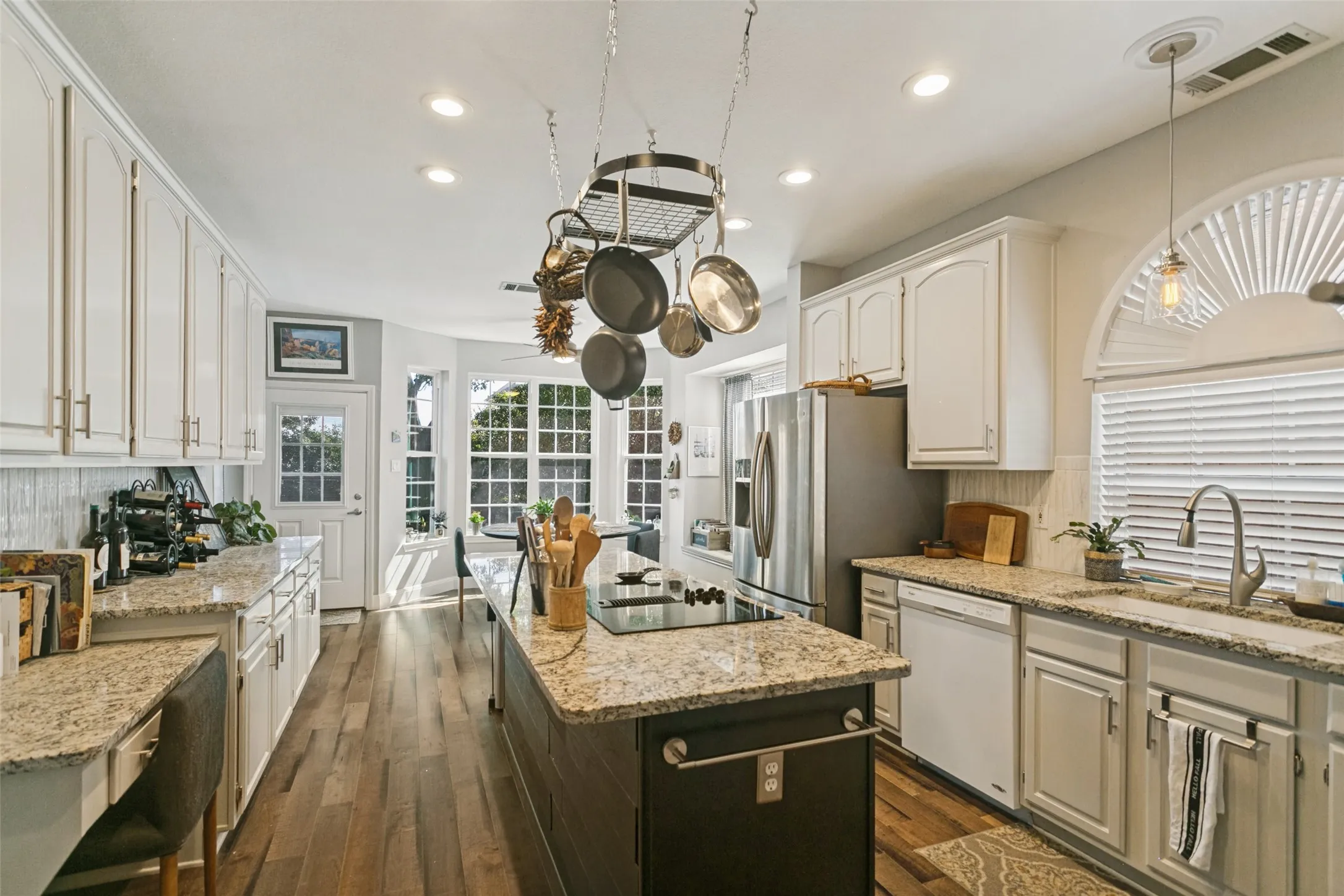 Kitchen featuring white shaker-style cabinetry, stone countertops, a center island with a built-in cooktop, recessed lighting, and wood-finish flooring