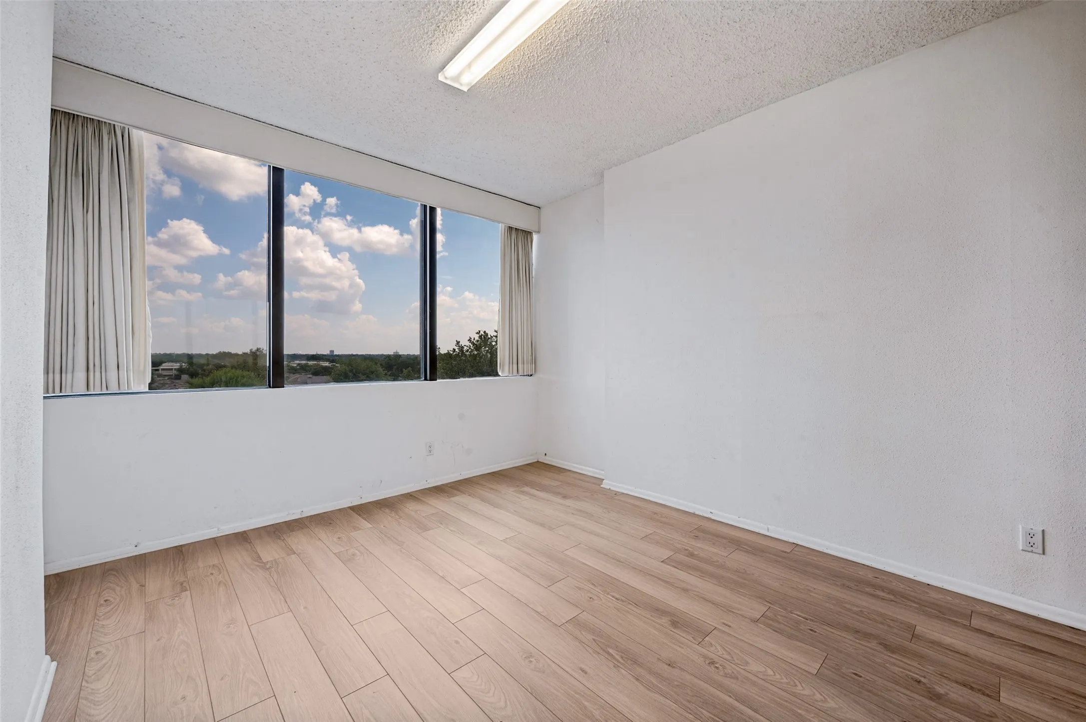 Expansive floor-to-ceiling windows featuring natural lighting and wood-finish flooring