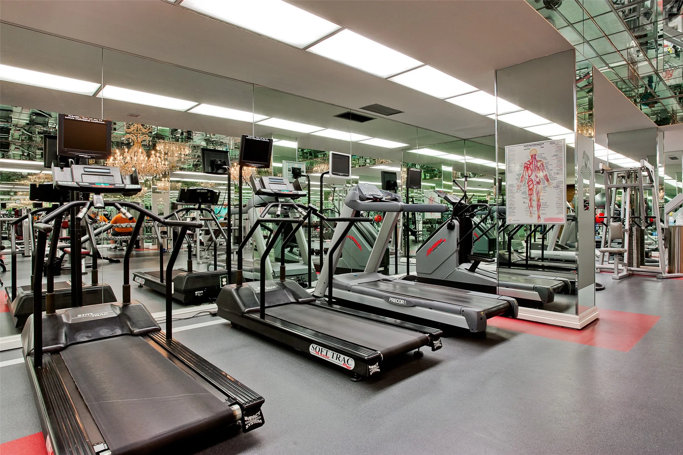 Fitness room featuring full-wall mirrored surfaces, recessed ceiling lighting, and resilient composite flooring