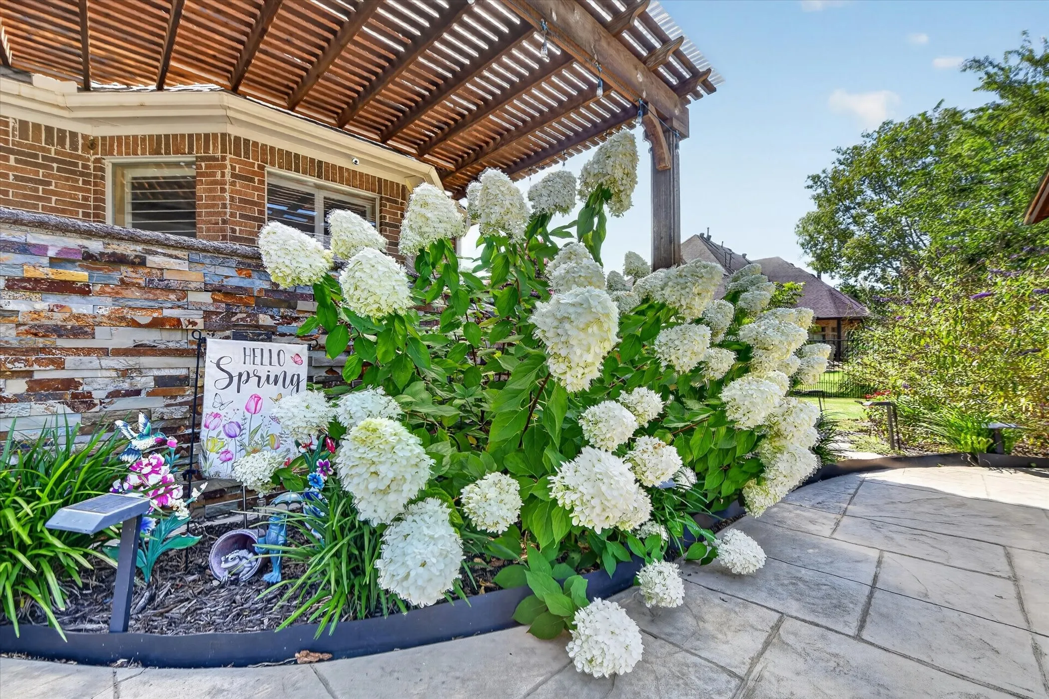 Patio featuring a stained wood pergola, natural stone veneer accent wall, and stone paver flooring