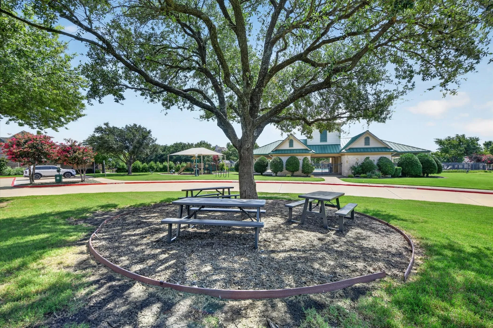 Community park area featuring expansive lawn, mature shade trees, and a pavilion structure