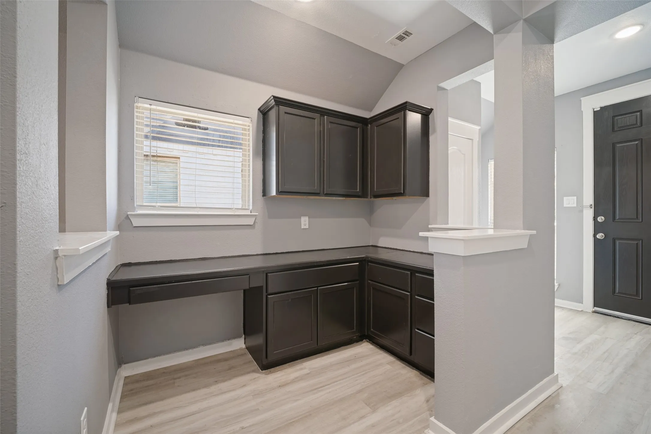 Built-in dark cabinetry with lower storage drawers, integrated desk surface, and wood-finish flooring