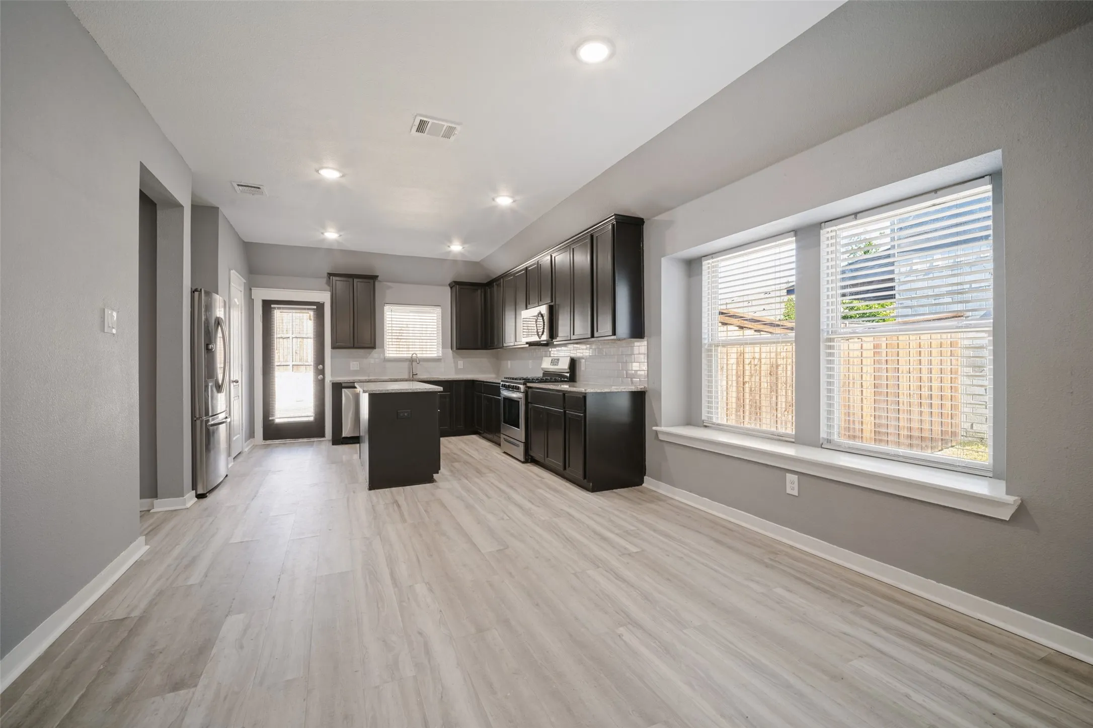 Kitchen featuring dark cabinetry, center island, light-toned wood-finish flooring, recessed lighting, and a window seat