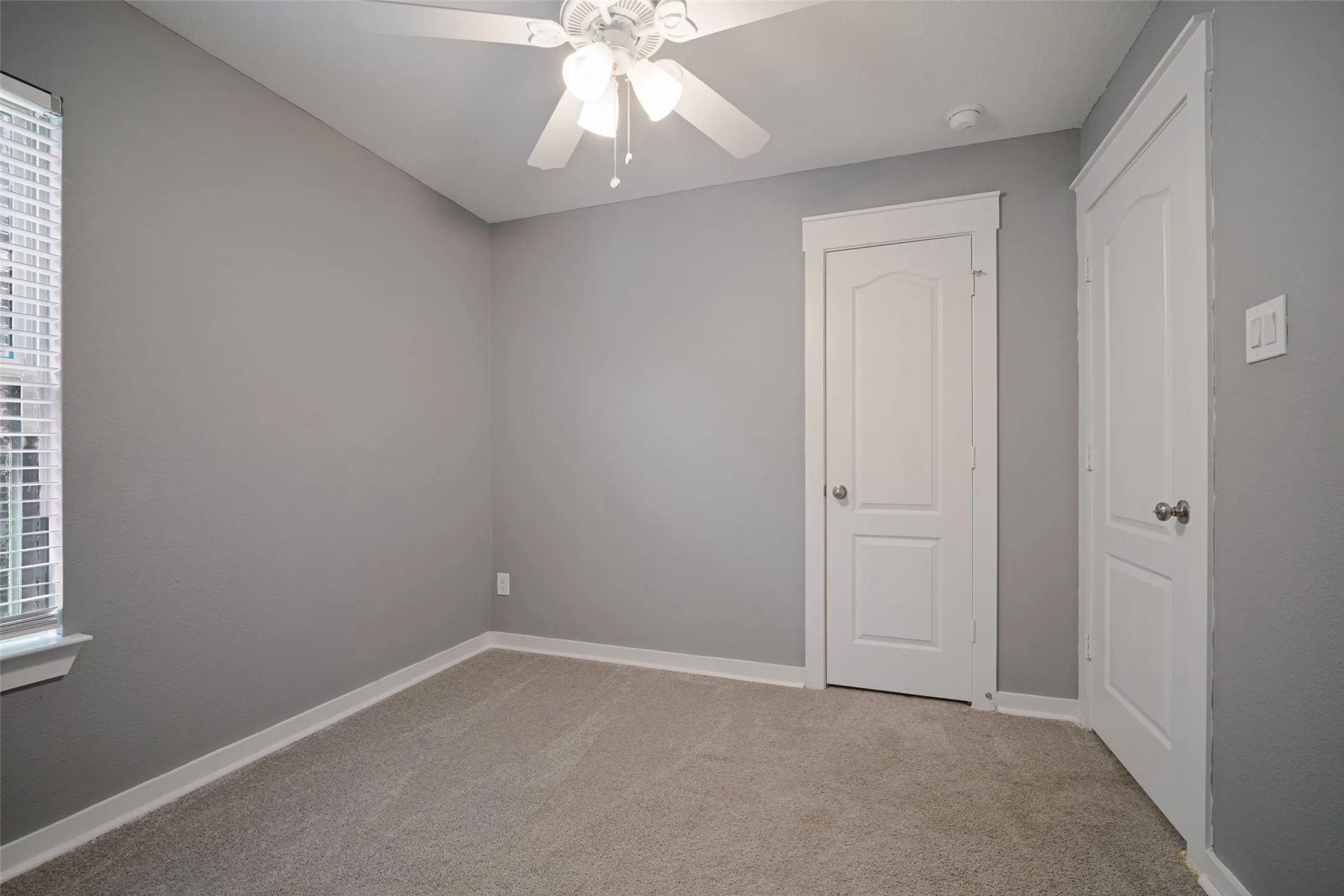 Room featuring wall-to-wall carpeting, neutral interior paint, a ceiling fan with integrated lighting, and two multi-panel interior doors