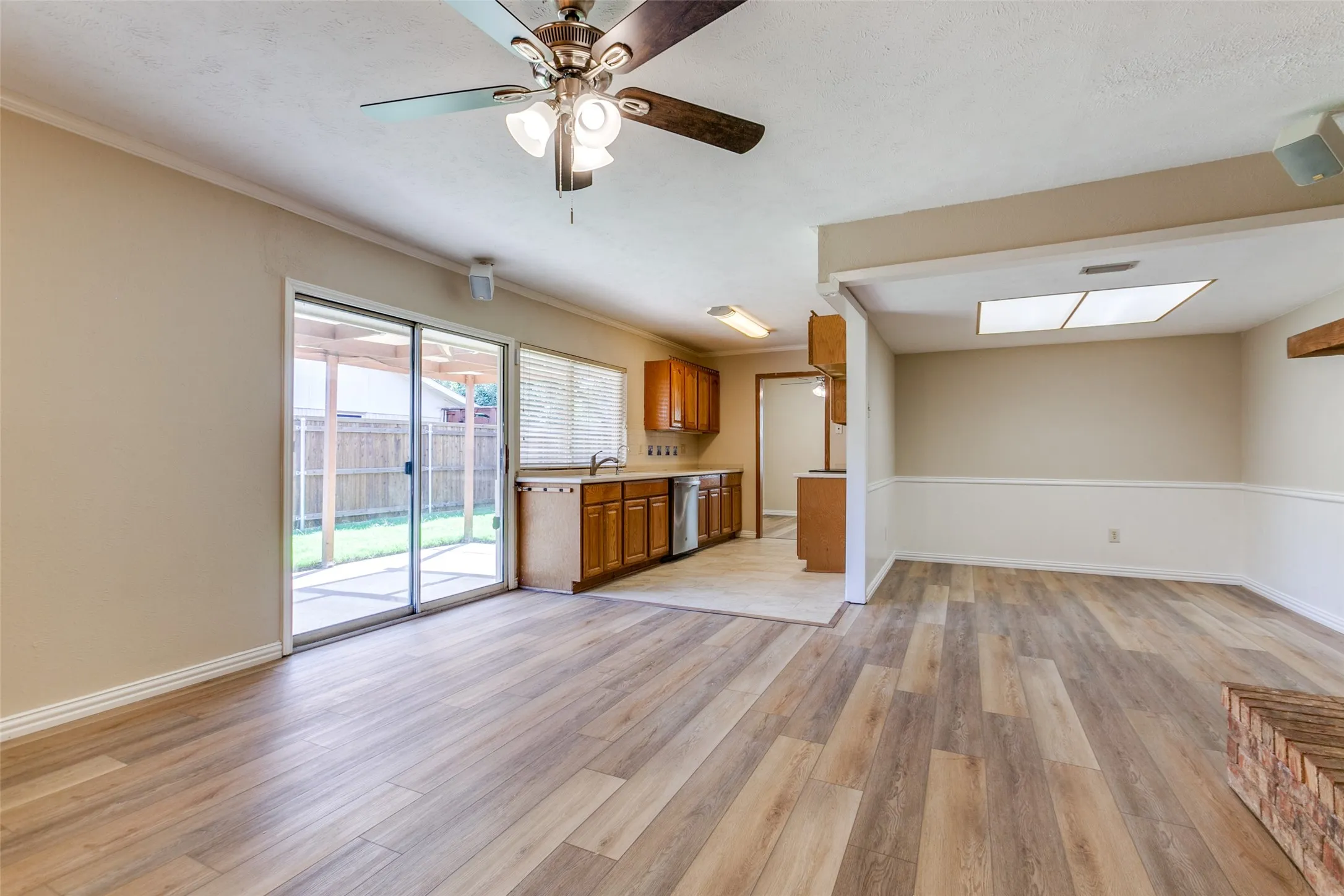 Wood-finish flooring, sliding glass patio door, wooden cabinetry, recessed and ceiling-mounted lighting, and a brick-accented fireplace feature