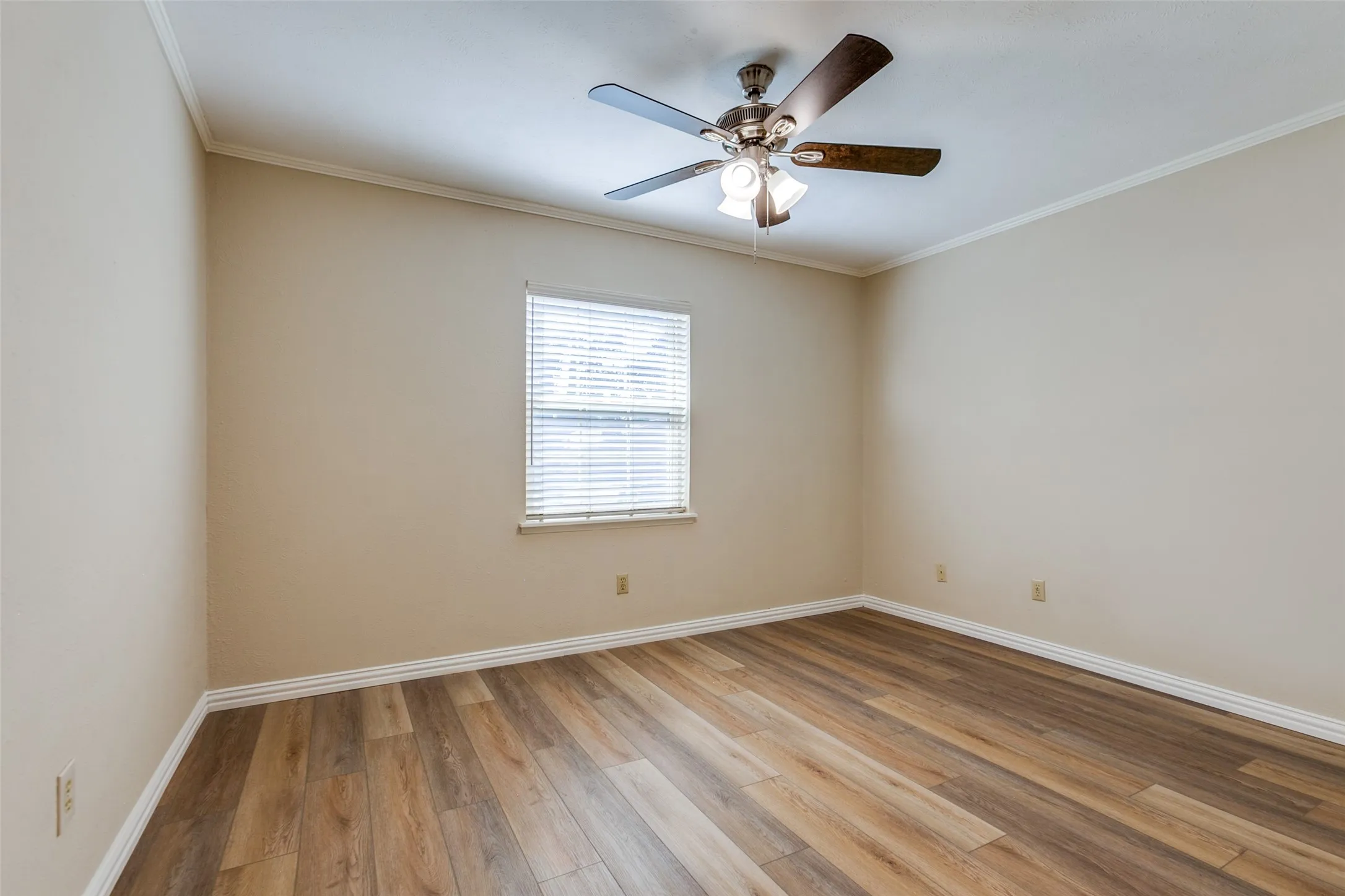 Room featuring wood-finish flooring, neutral wall paint, a multi-blade ceiling fan with integrated lighting, and a window with horizontal blinds