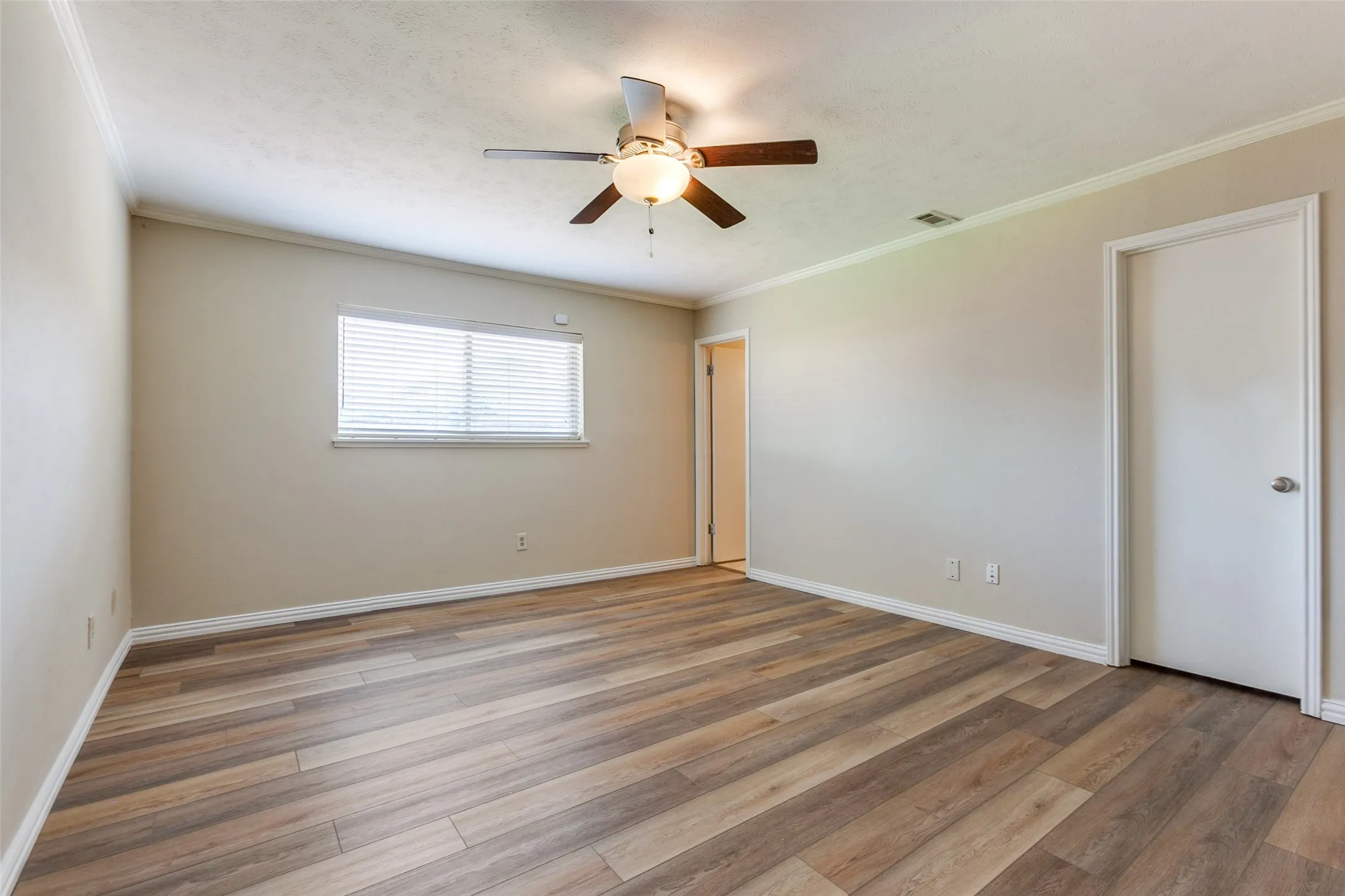 Interior space featuring wood-finish flooring, neutral wall paint, and a ceiling-mounted light fixture with a fan