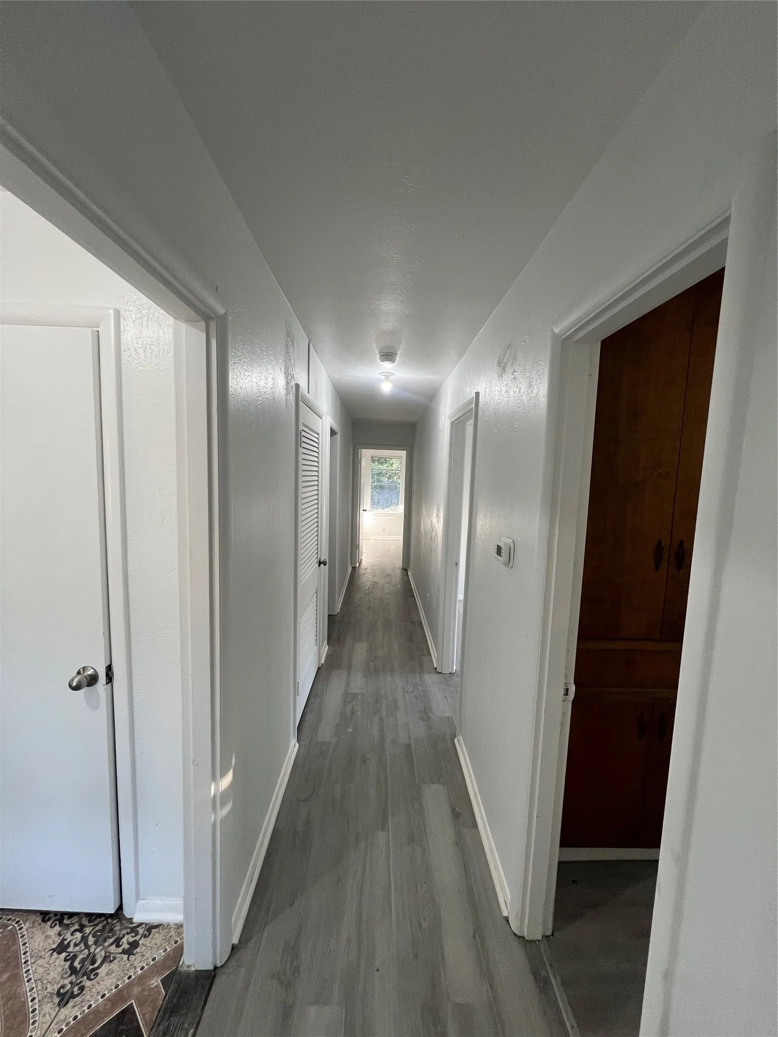 Hallway featuring wood-finish flooring, a ceiling-mounted light fixture, and built-in wood cabinetry
