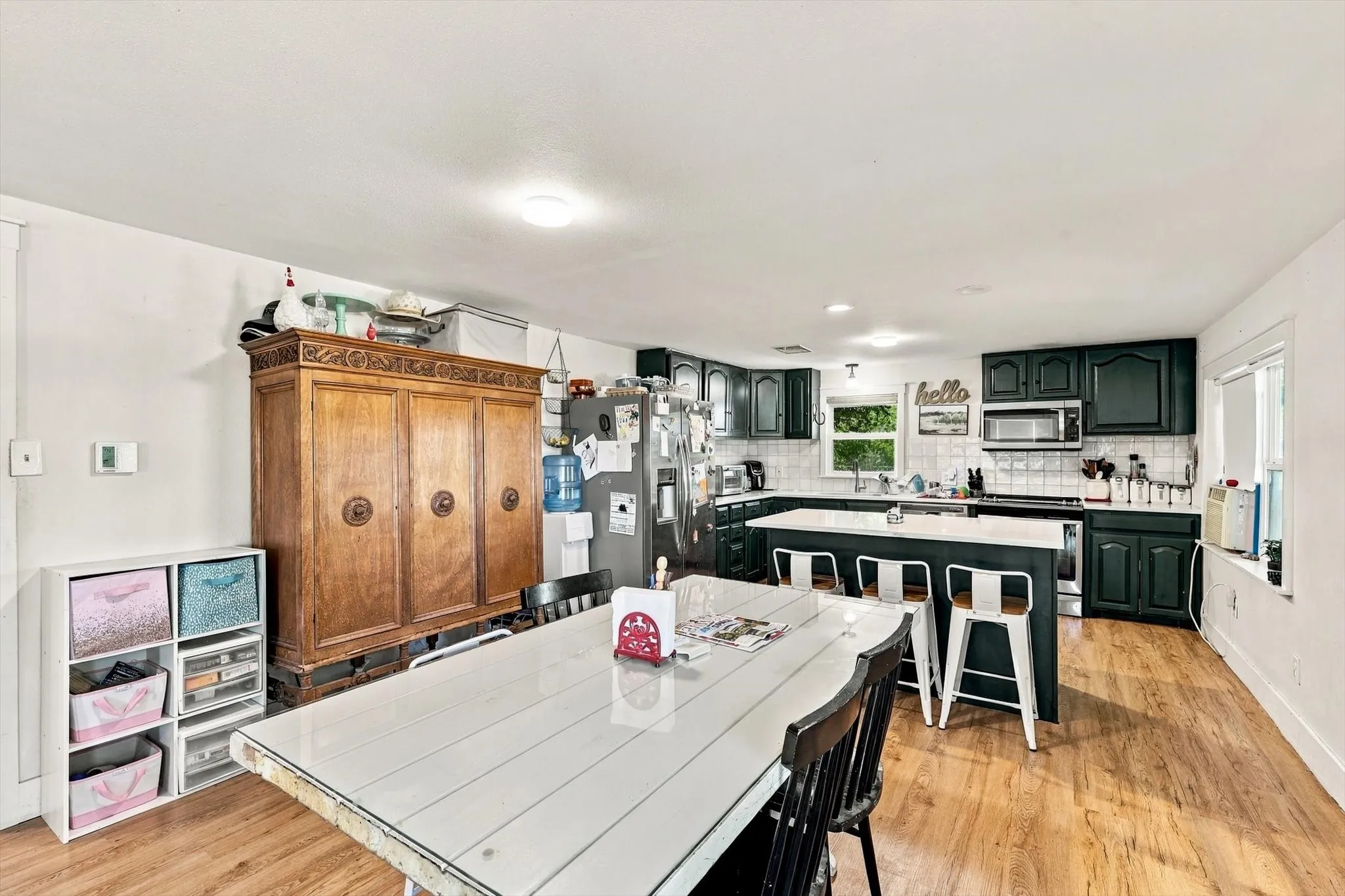 Kitchen featuring dark cabinetry, a central island with bar seating, tile backsplash, stainless steel appliances, and wood-finish flooring