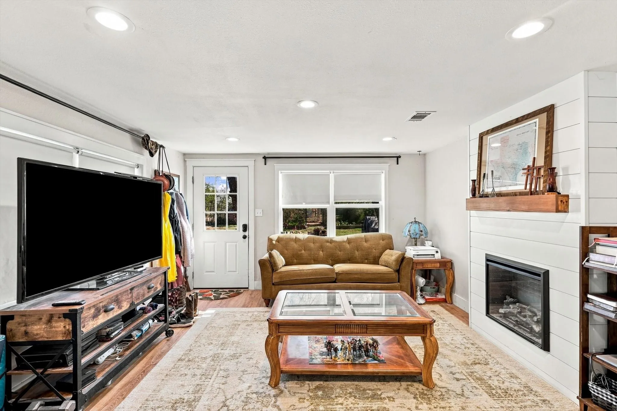 Fireplace featuring a wood mantel and shiplap surround, recessed lighting, and wood-finish flooring