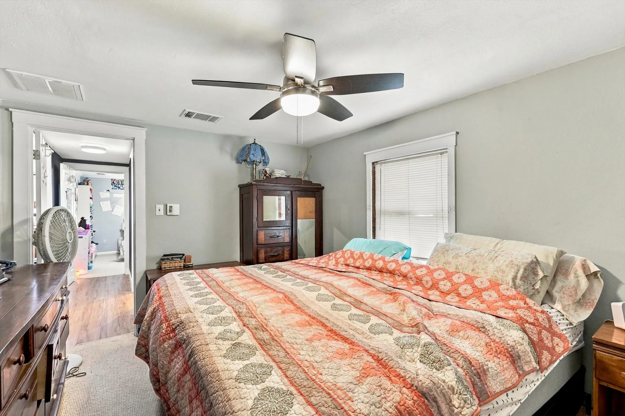 Room featuring neutral wall paint, a satin-finish ceiling fan with integrated lighting, and white window casing