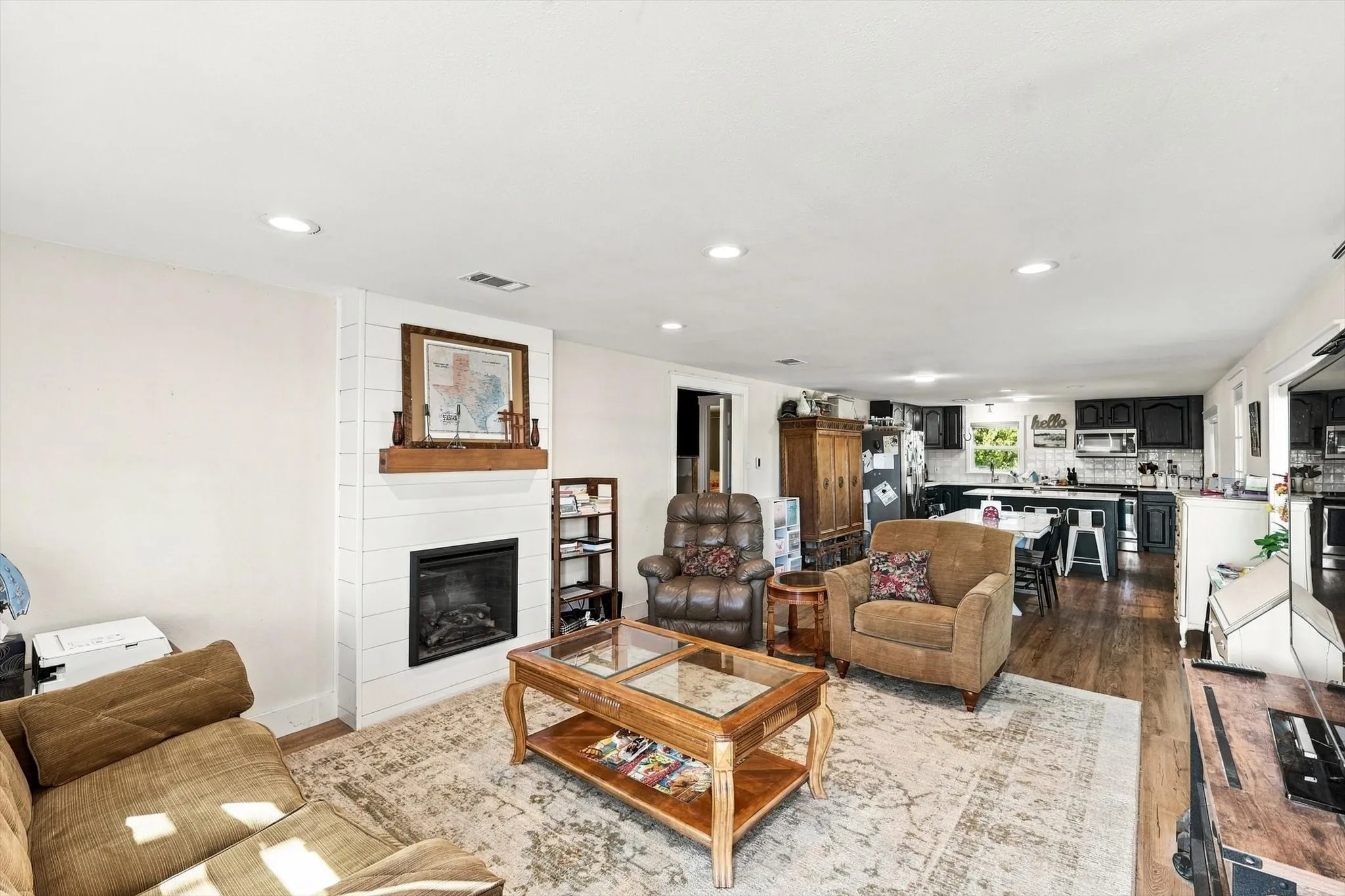 Living area featuring wood-finish flooring, recessed lighting, and a fireplace with a white shiplap surround and a wood mantel