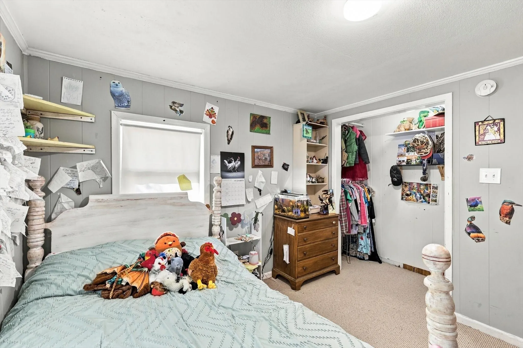 Bedroom featuring neutral wall paneling, wall-to-wall carpeting, and a closet with built-in shelving