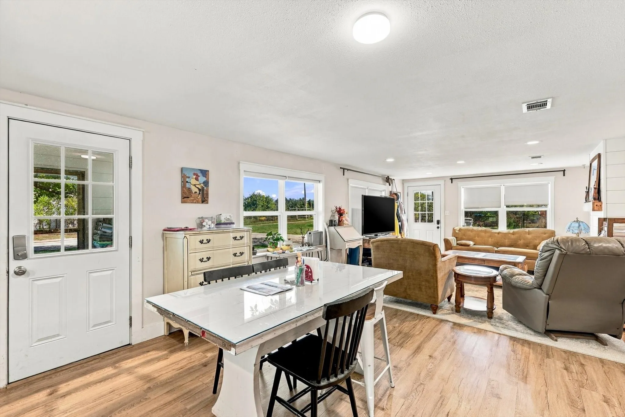 Open-concept interior featuring wood-finish flooring, multi-pane glass entry doors, recessed lighting, and large windows