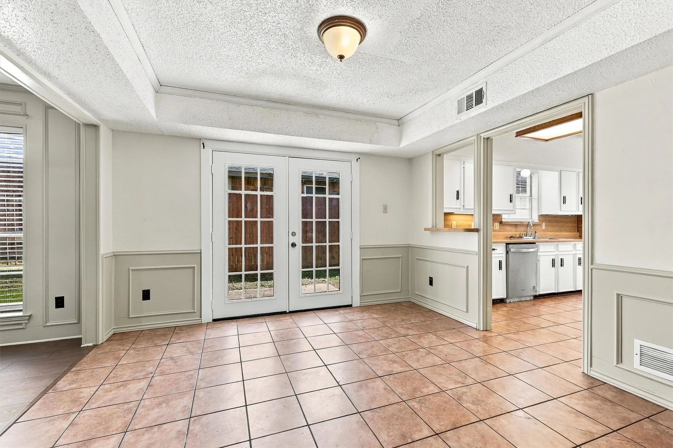 Ceramic tile flooring, full-lite French doors, wainscoting, and a kitchen pass-through window with built-in counter