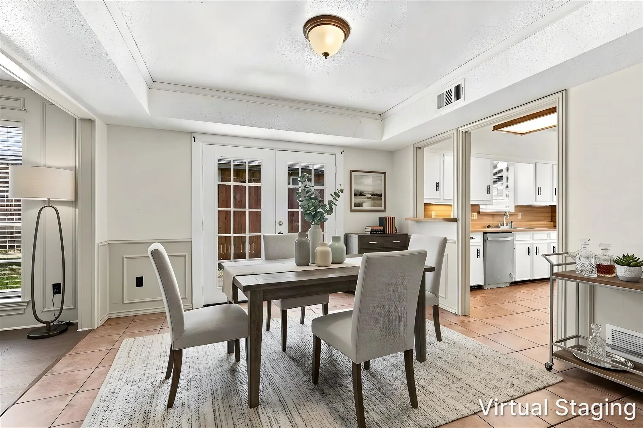 Dining area featuring dual-pane French doors with muntins, tiled flooring, crown molding, and wainscoting