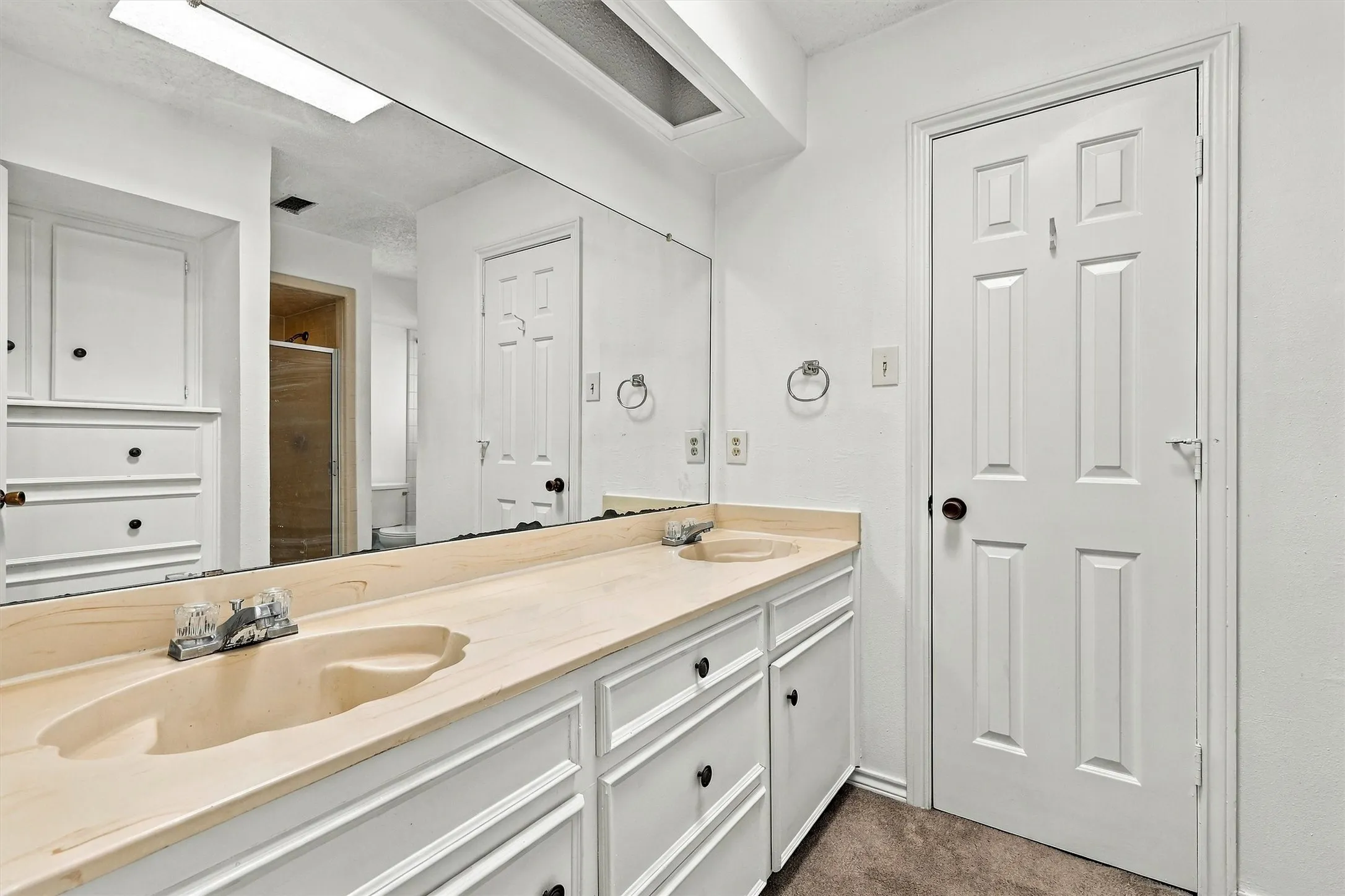 Dual-basin vanity featuring integrated sinks, expansive wall-to-wall mirror, extensive white built-in cabinetry, and recessed lighting