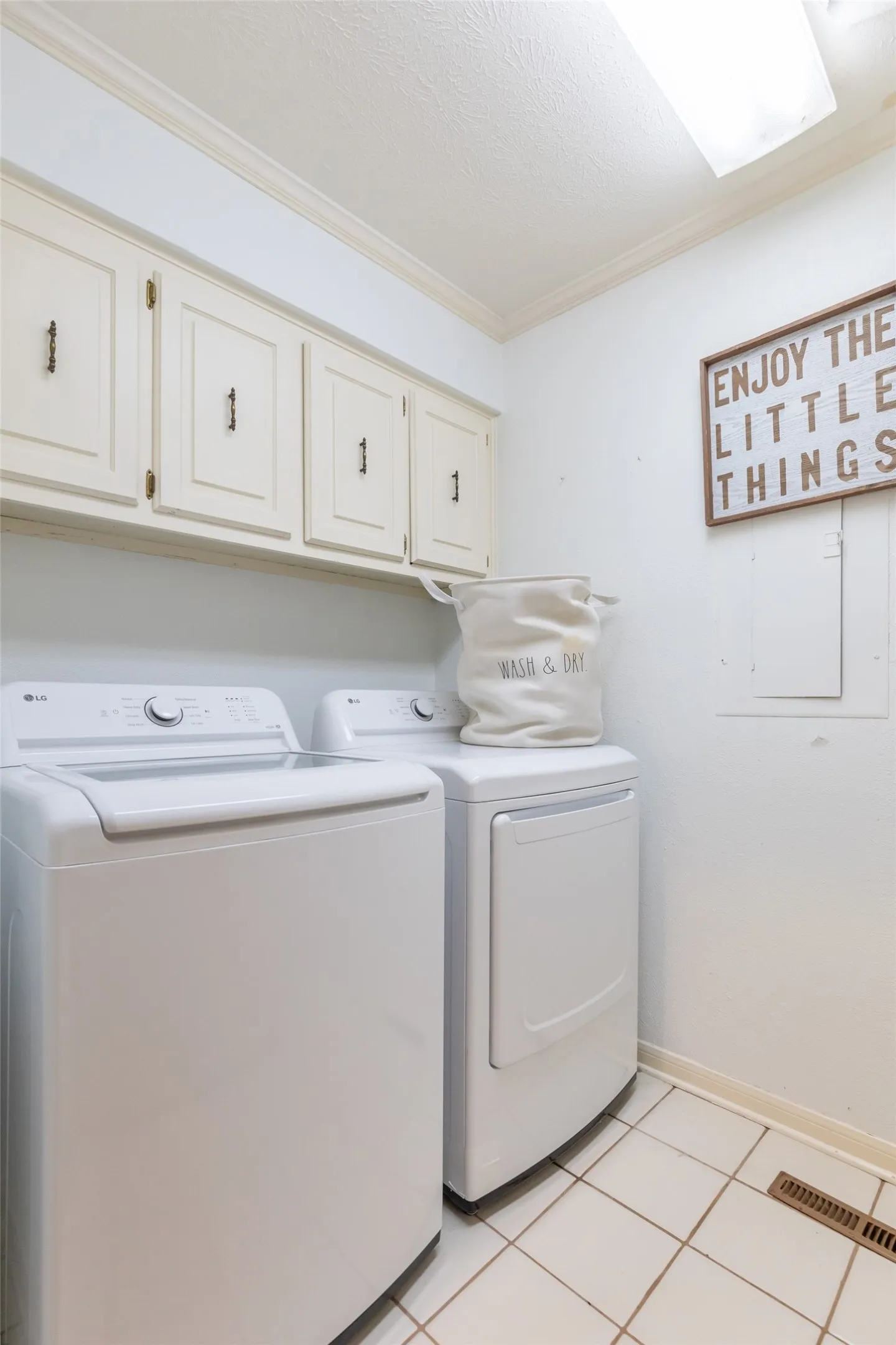 Laundry room featuring white tile flooring and wall-mounted cabinetry with matte black hardware