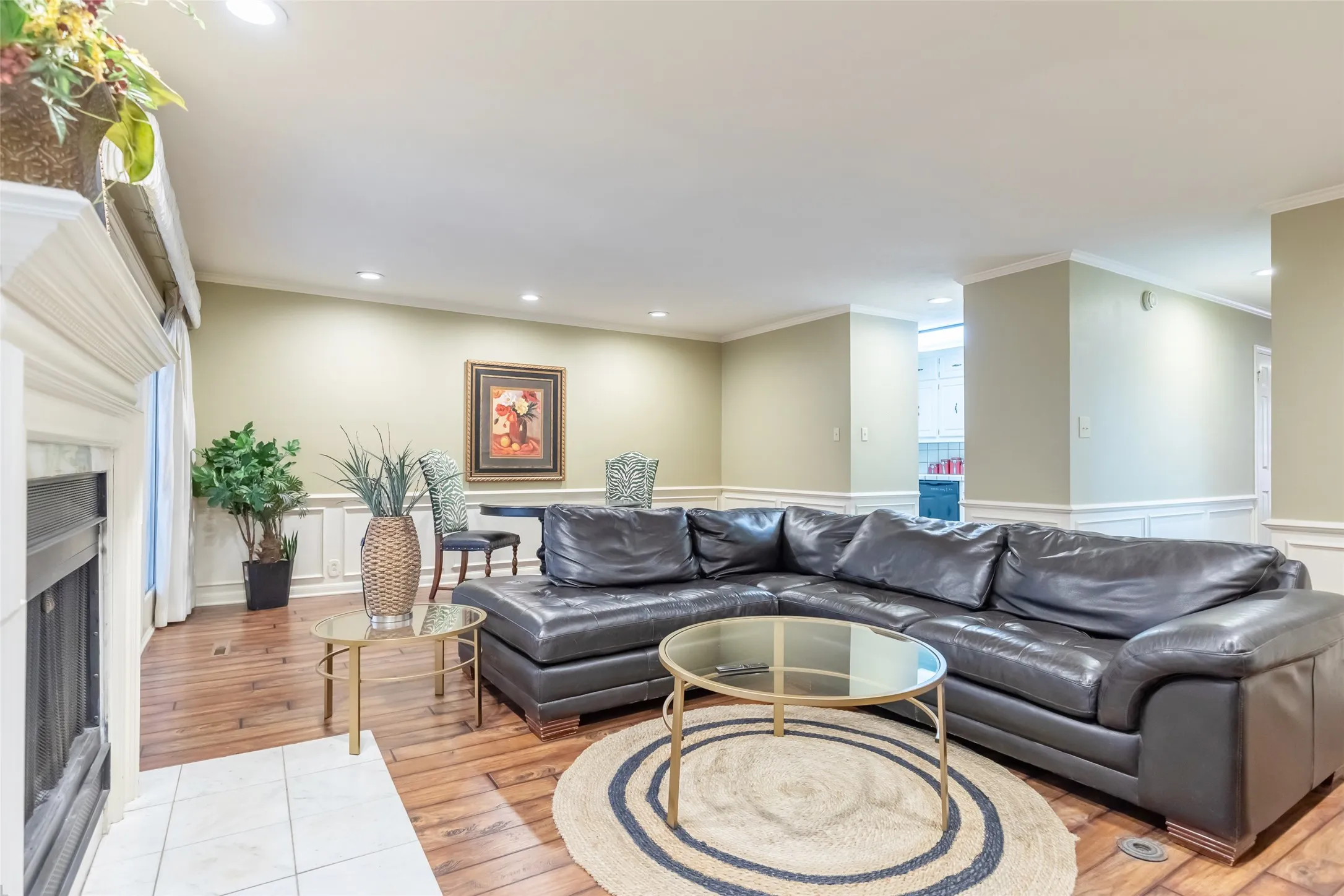 Wood-finish flooring, fireplace with a decorative mantel, recessed lighting, and wall wainscoting