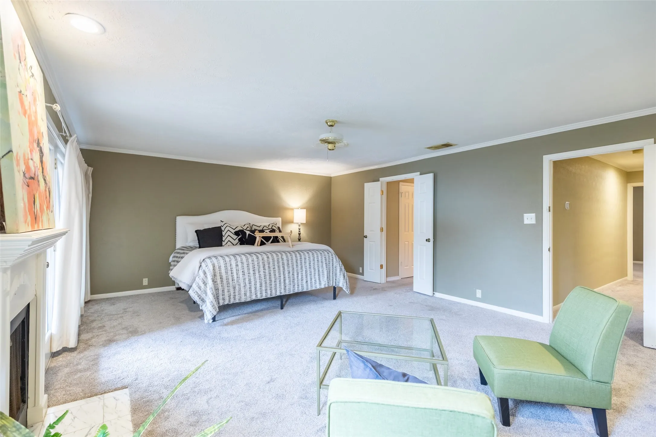 Neutral-toned bedroom featuring carpeted flooring, a fireplace with a decorative mantel, and double interior doors