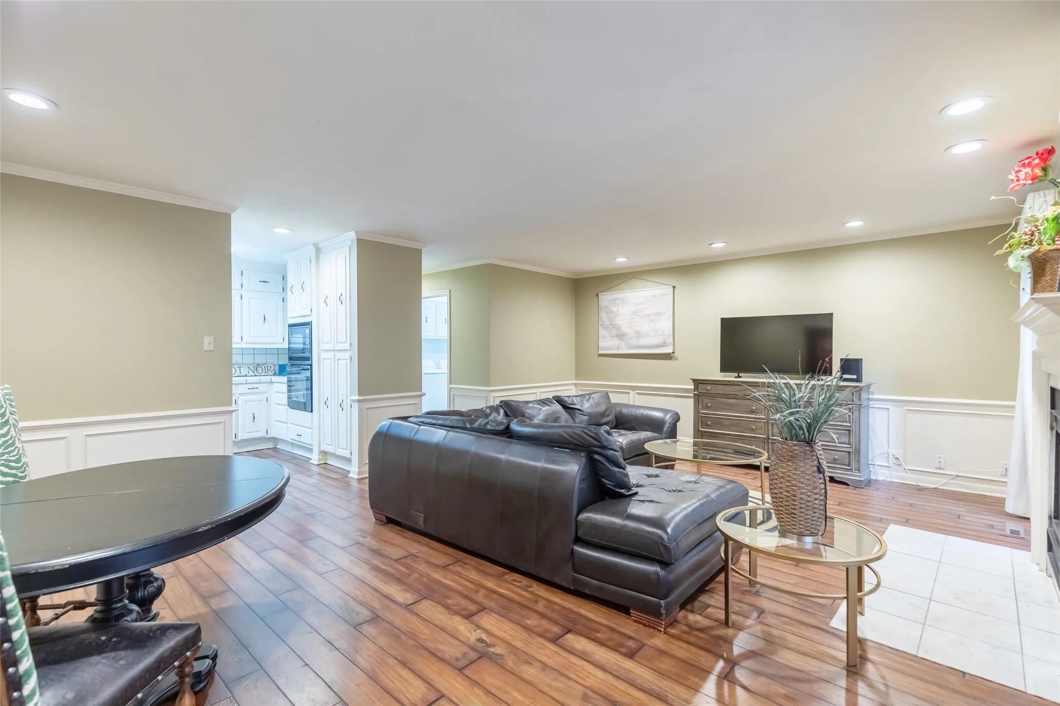 Wood-finish flooring, white wainscoting, recessed lighting, built-in floor-to-ceiling cabinetry, and a tile-surround fireplace