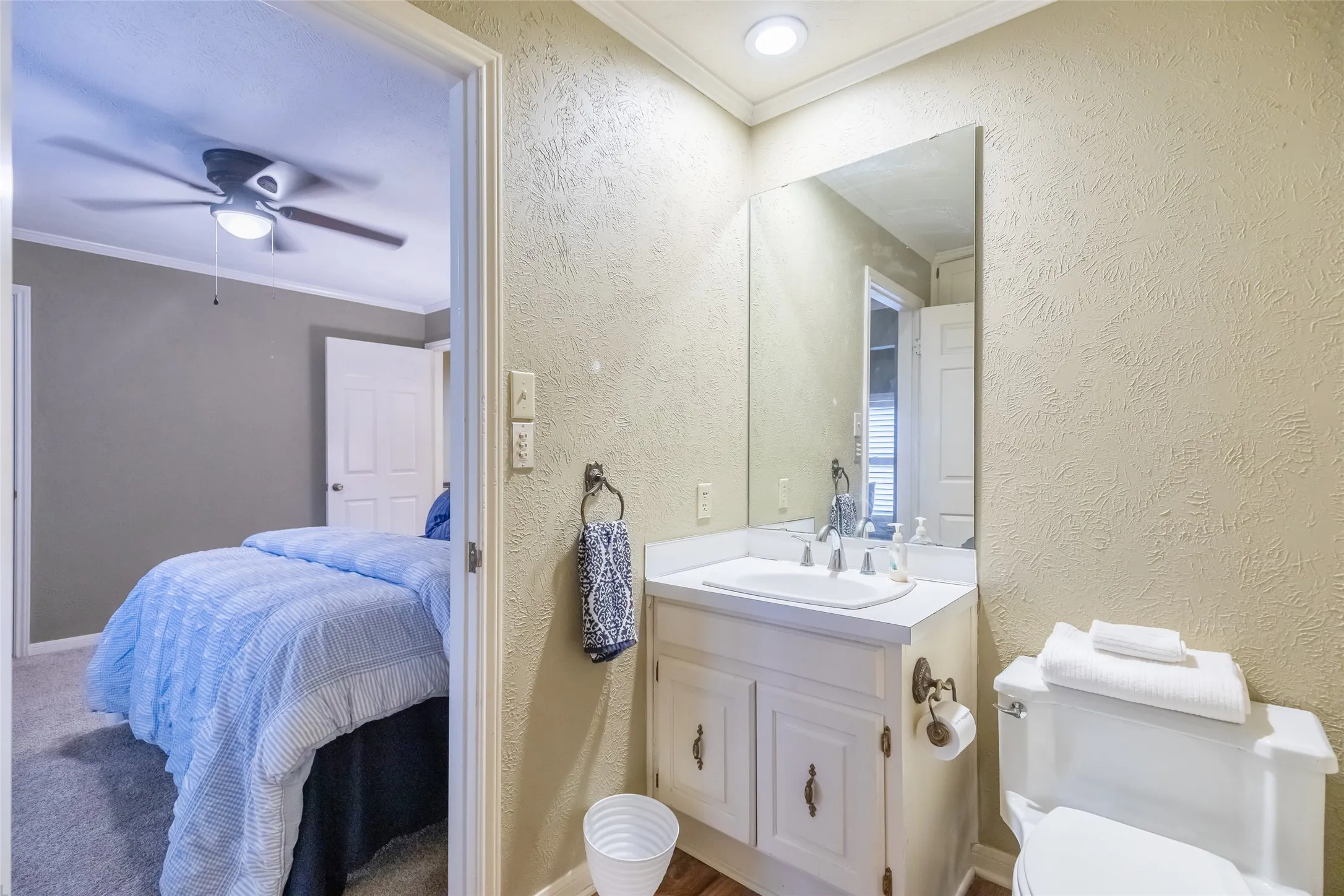 Bathroom vanity featuring a white cabinet, countertop with integrated sink, chrome widespread faucet, and a wall-mounted mirror
