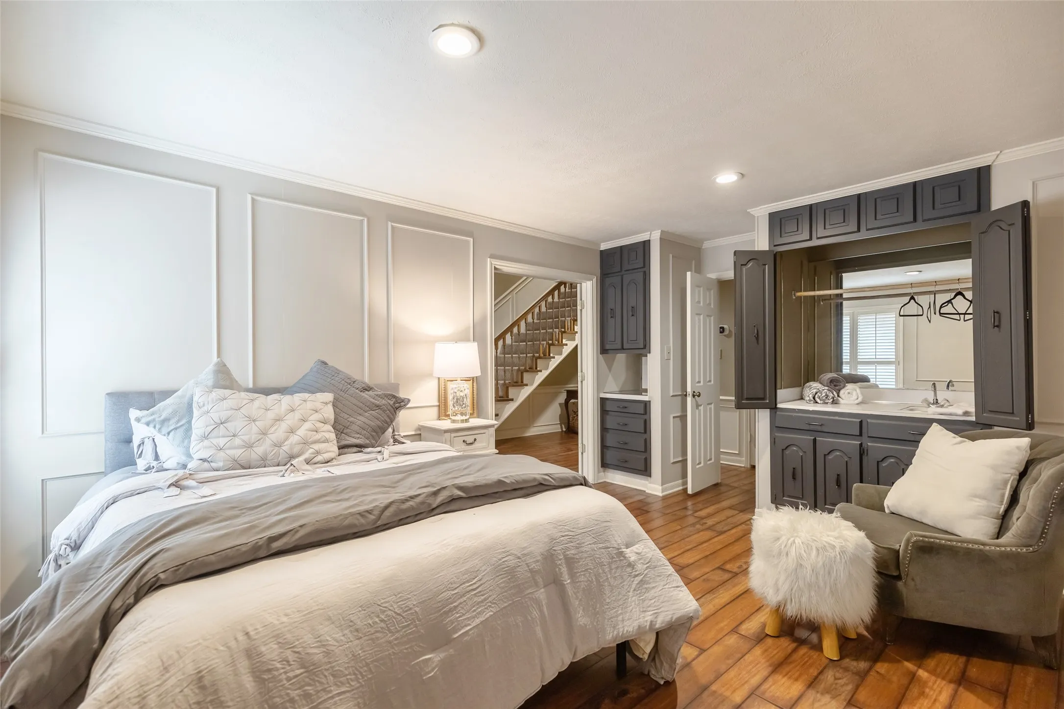 Wood-finish flooring, paneled wall detailing, and built-in dark cabinetry with an integrated vanity mirror