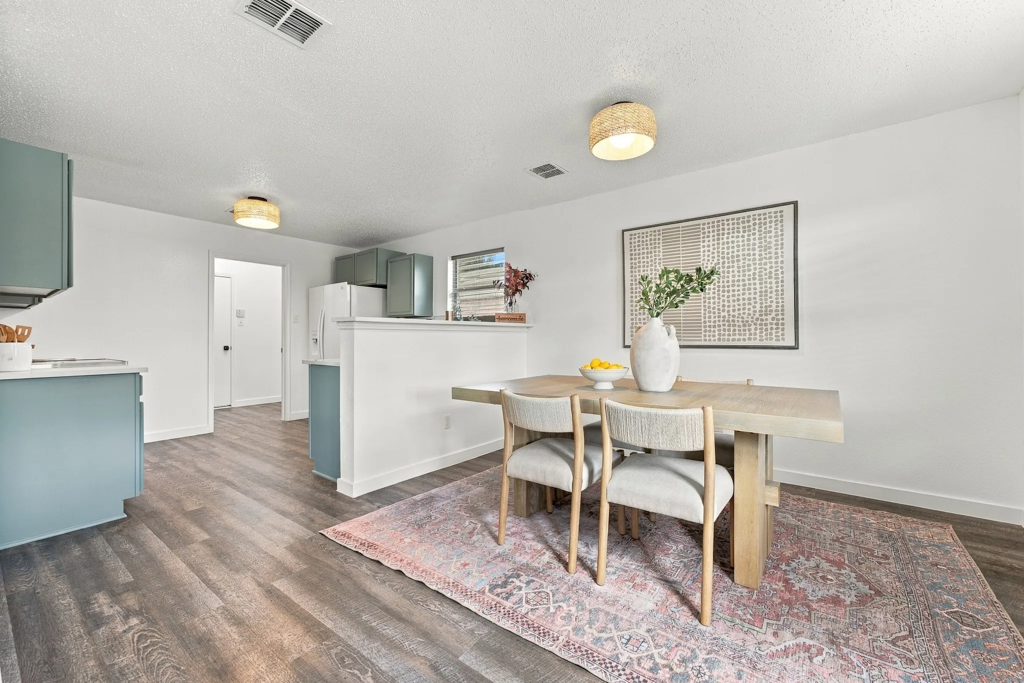 Kitchen and dining area featuring wood-finish flooring, matte blue cabinetry, and dual drum-style ceiling-mounted light fixtures
