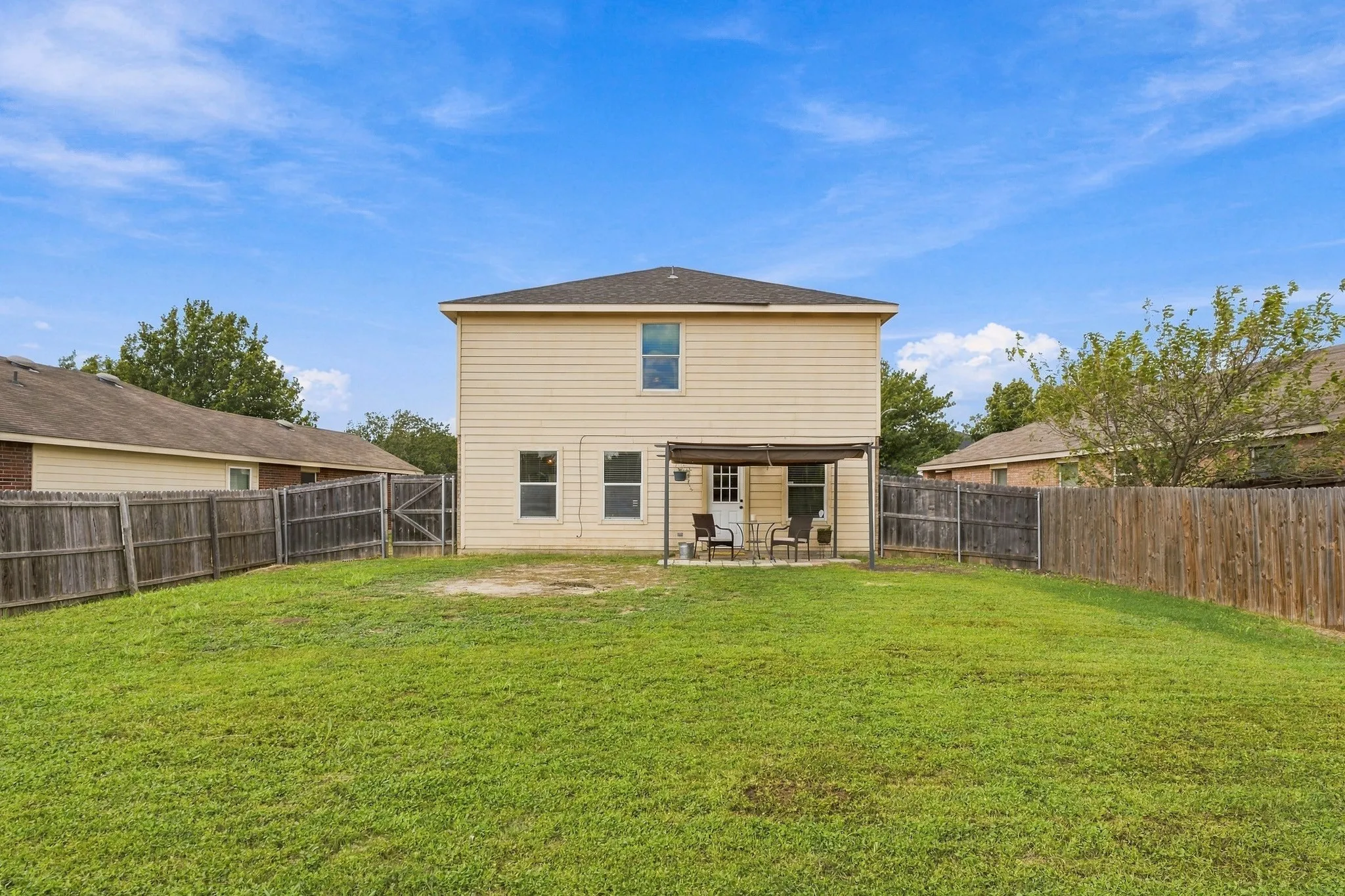 Rear exterior featuring horizontal lap siding, a covered concrete patio, and a fenced backyard