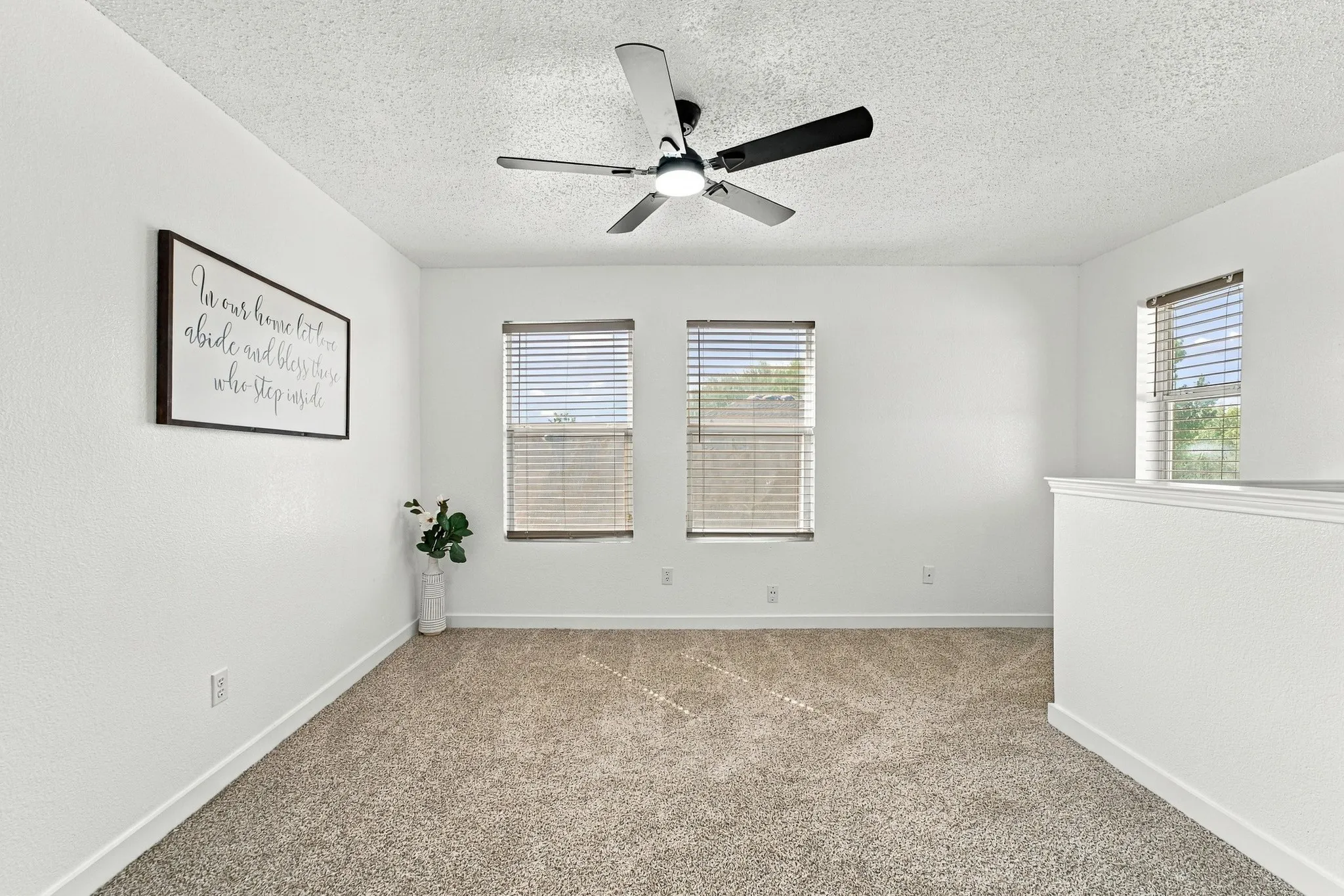 Neutral wall finish, wall-to-wall carpeting, ceiling fan with integrated lighting, and dual windows with horizontal blinds