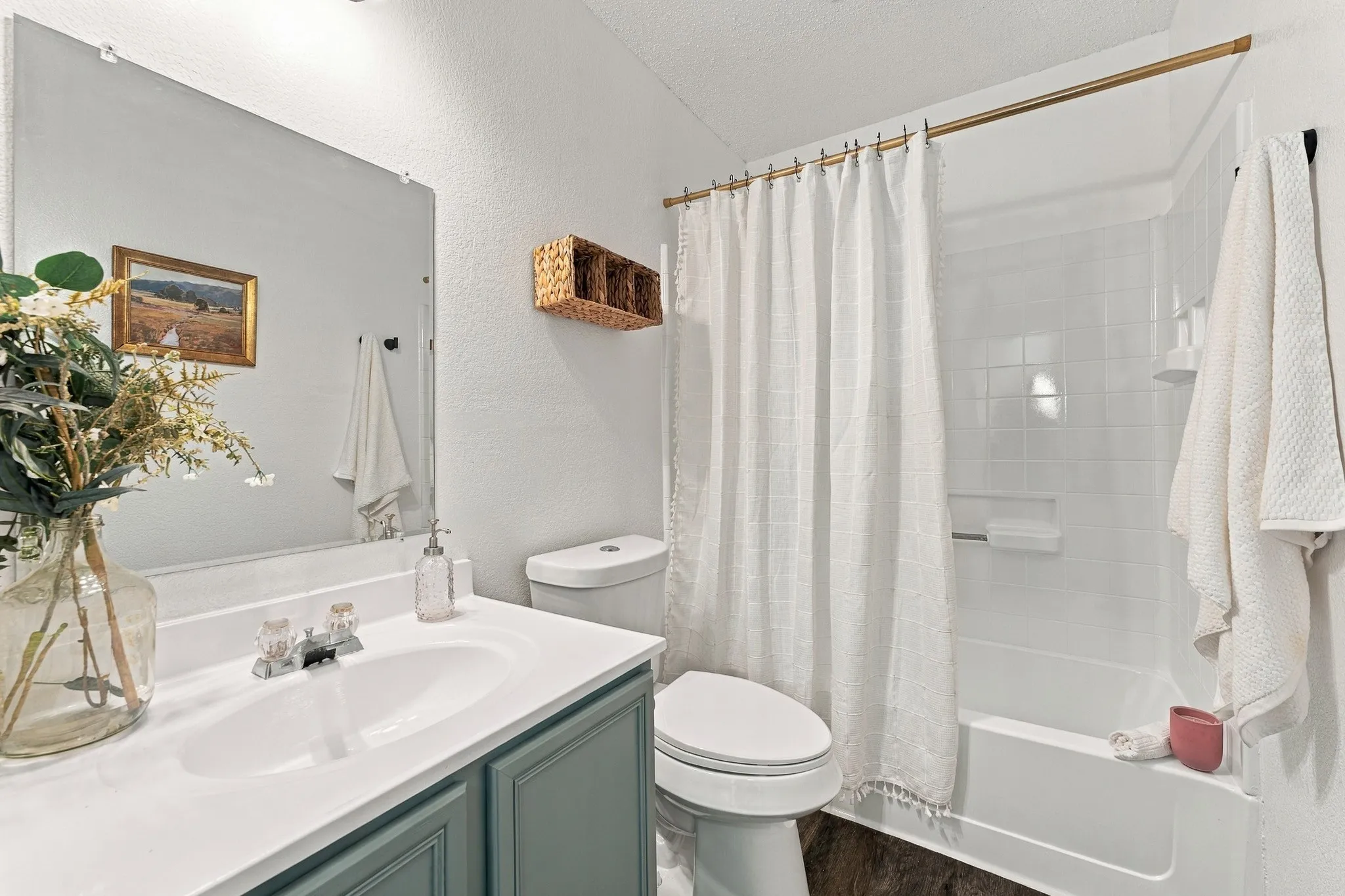 Bathroom featuring a vanity with a white countertop and integrated sink, frameless wall-mounted mirror, and a tub-shower combination with white tile surround