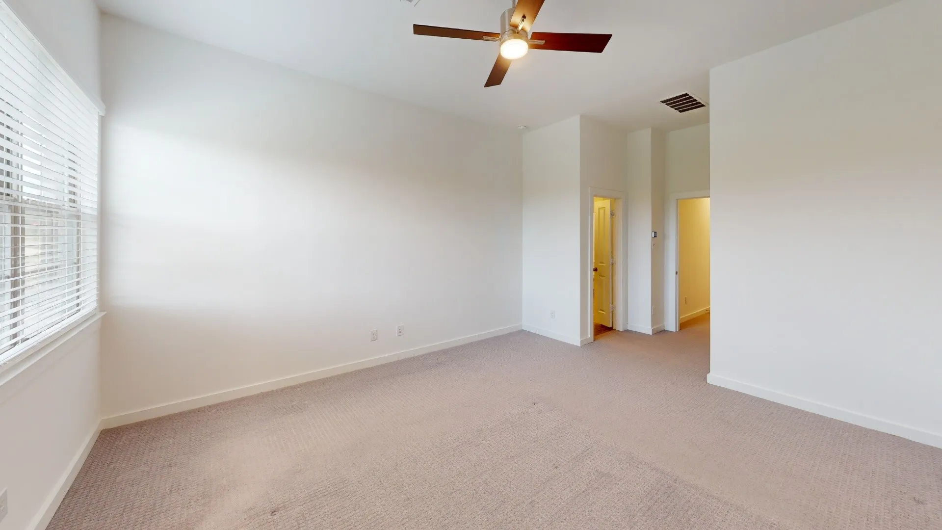 Neutral interior room featuring high ceilings, wall-to-wall carpeting, window blinds, and a ceiling fan with integrated lighting