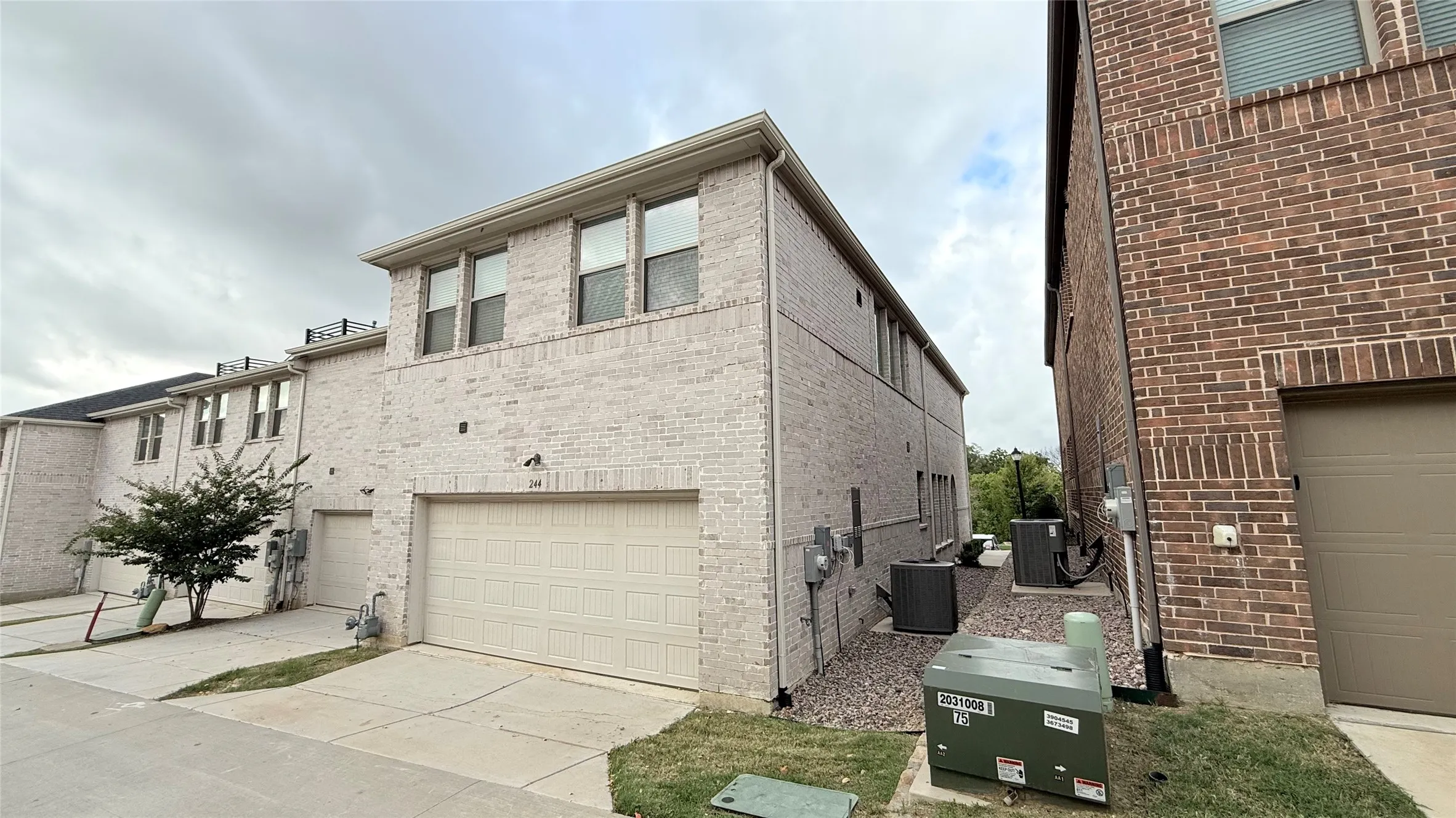 Light-toned brick exterior featuring multi-level architecture and attached two-car garage