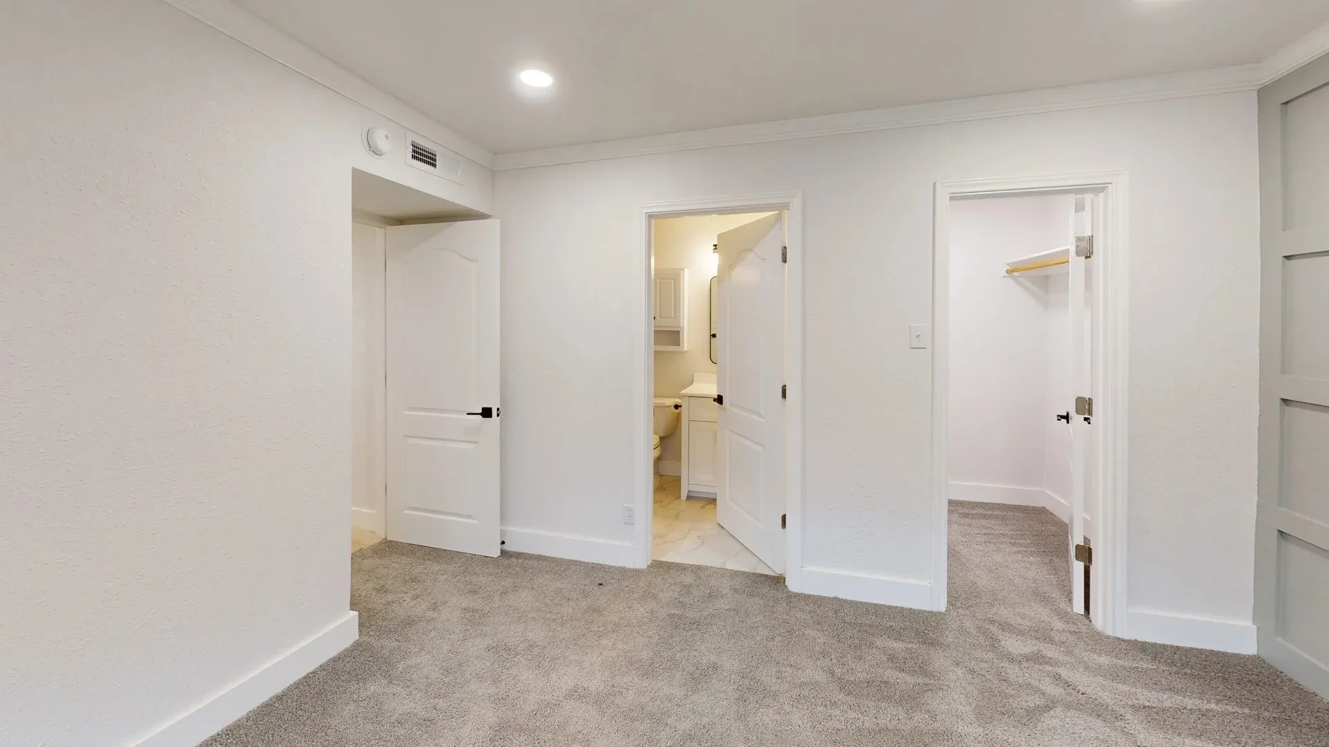 Neutral carpeted flooring, recessed lighting, crown molding, paneled wall accent, and multiple interior doors with matte black hardware