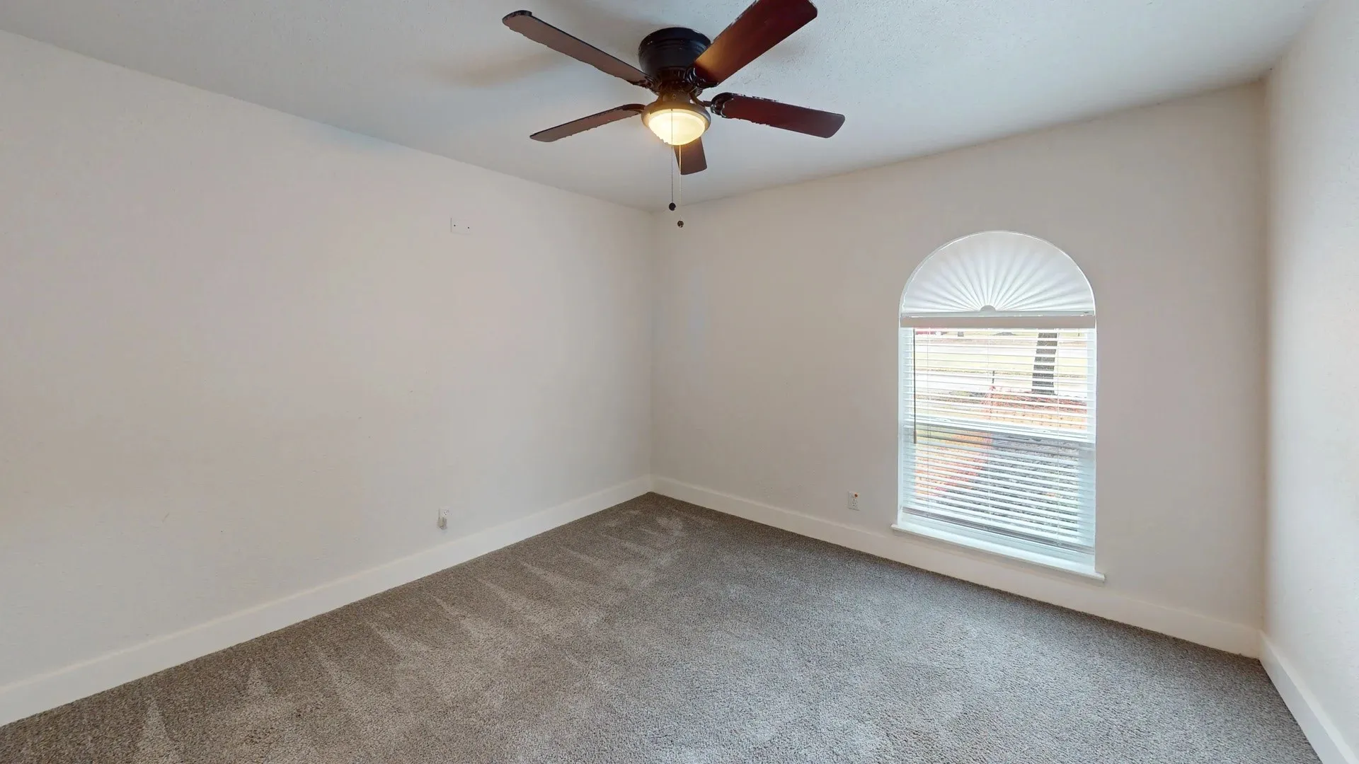 Neutral-toned carpeted flooring, vaulted arched window, and overhead ceiling fan with light fixture