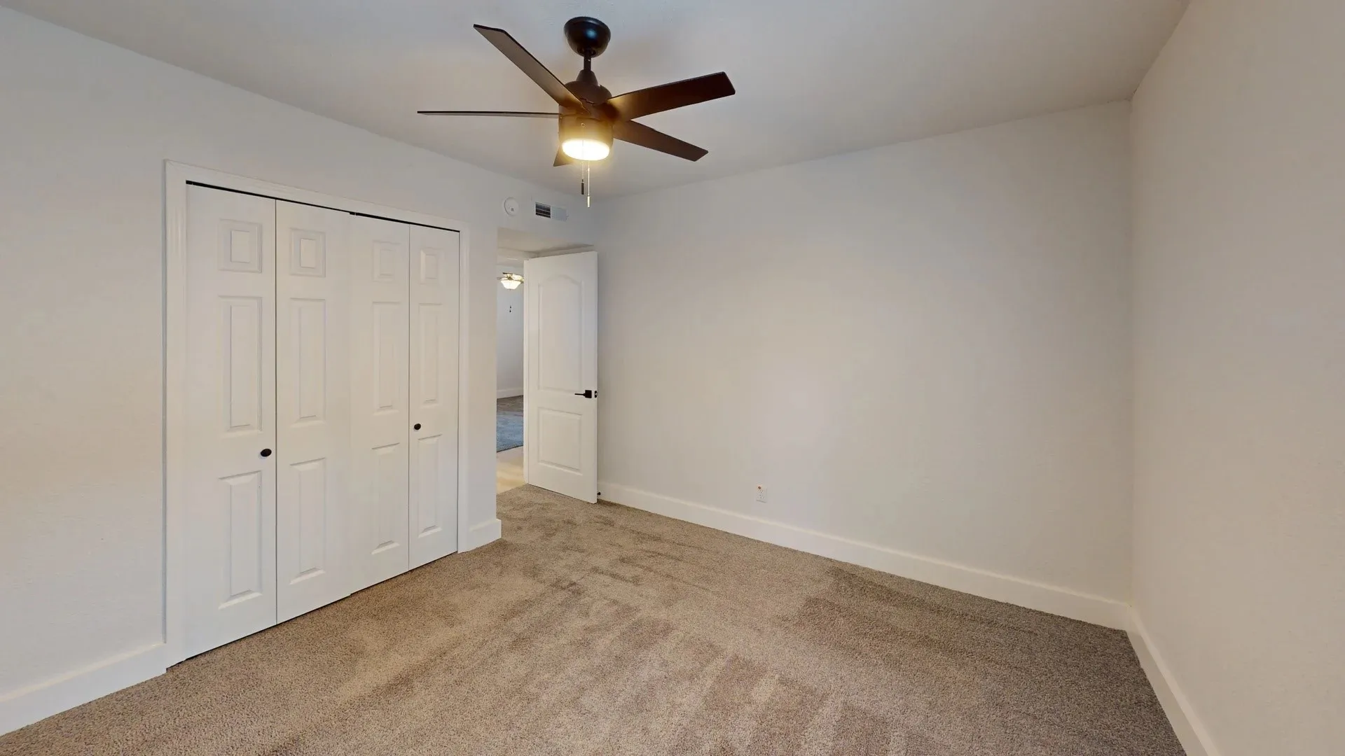 Neutral wall finish, wall-to-wall carpeting, bi-fold closet doors, and a ceiling fan with integrated lighting
