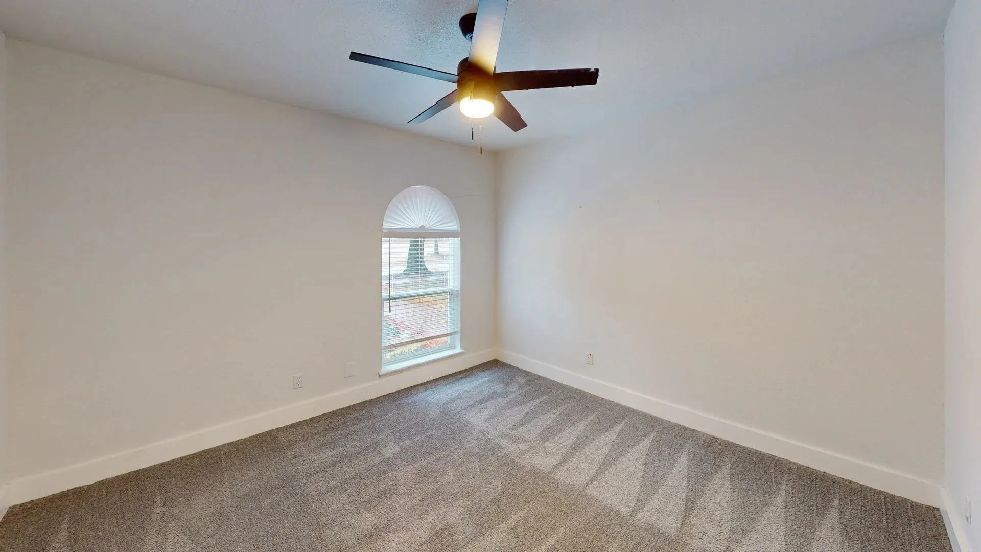 Room featuring neutral carpeting, an arched window, and a ceiling fan with integrated lighting