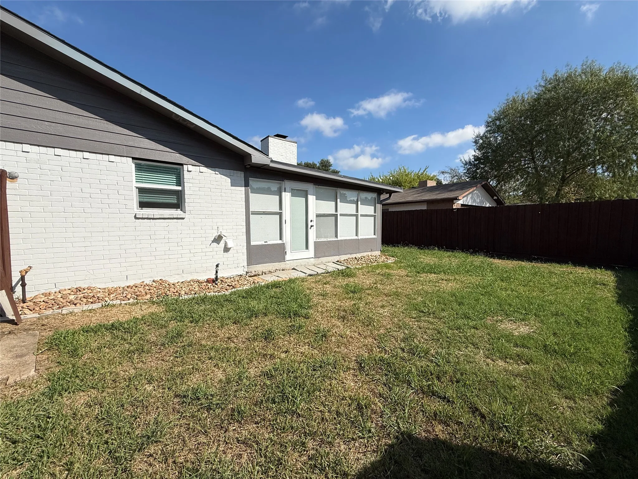 Exterior facade featuring painted brick, horizontal siding, an integrated chimney, and a fenced backyard