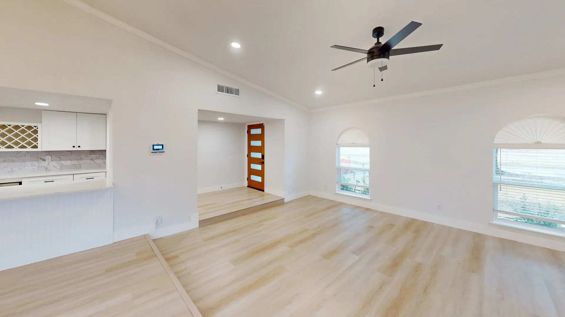 Vaulted ceilings, wood-finish flooring, recessed lighting, arched windows, and a wood-panel front door with glass inserts