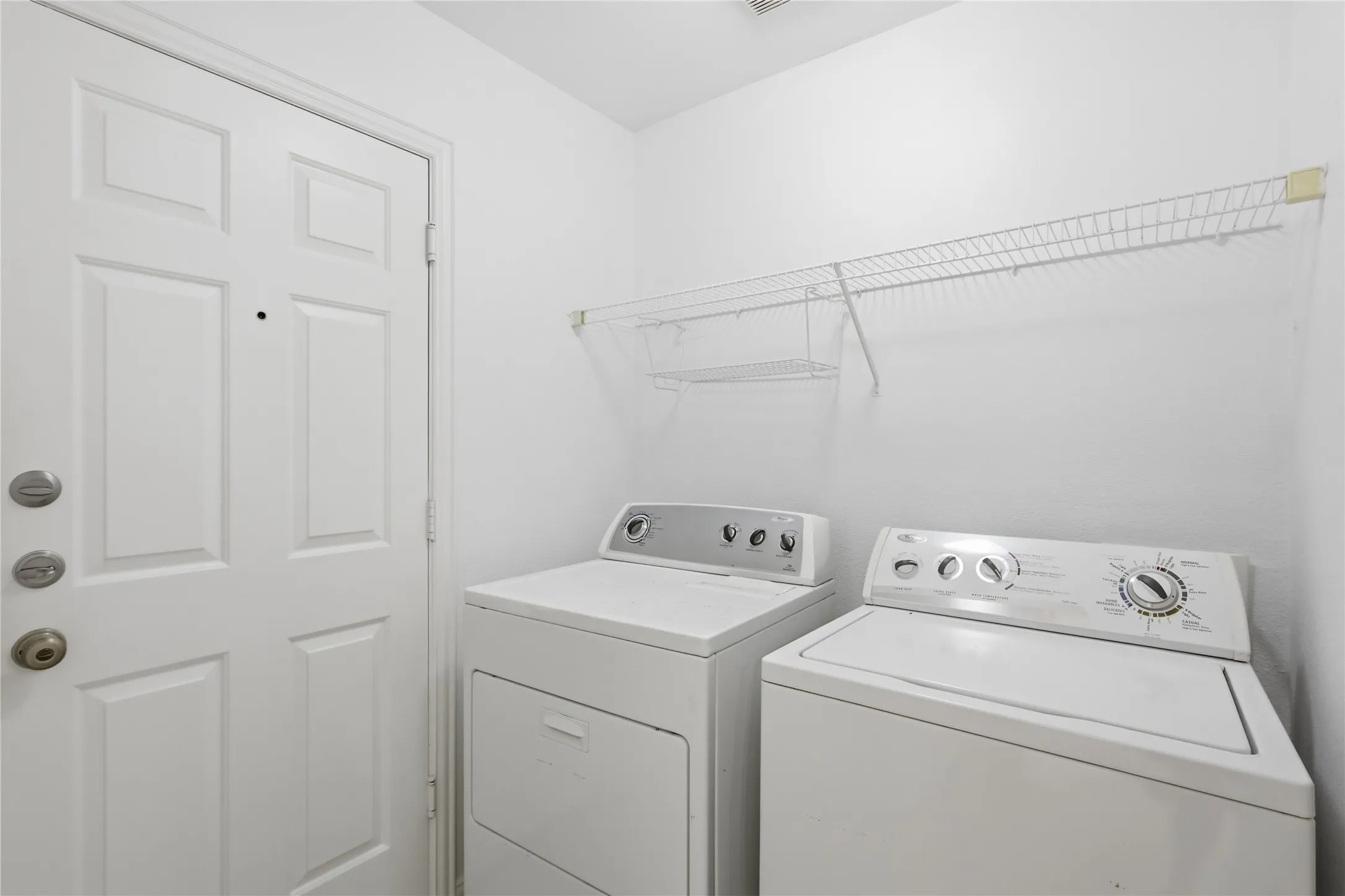 Laundry space featuring a paneled door, built-in wire shelving, and laundry appliances