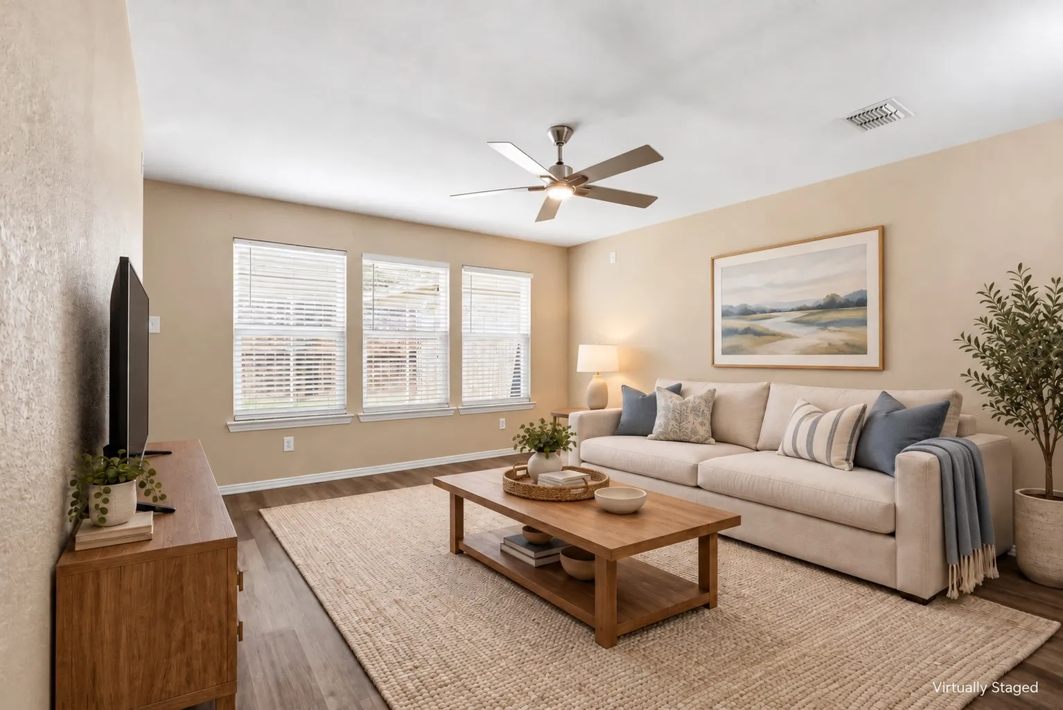 Living space featuring wood-finish flooring, a multi-blade ceiling fan, and triple windows with horizontal blinds