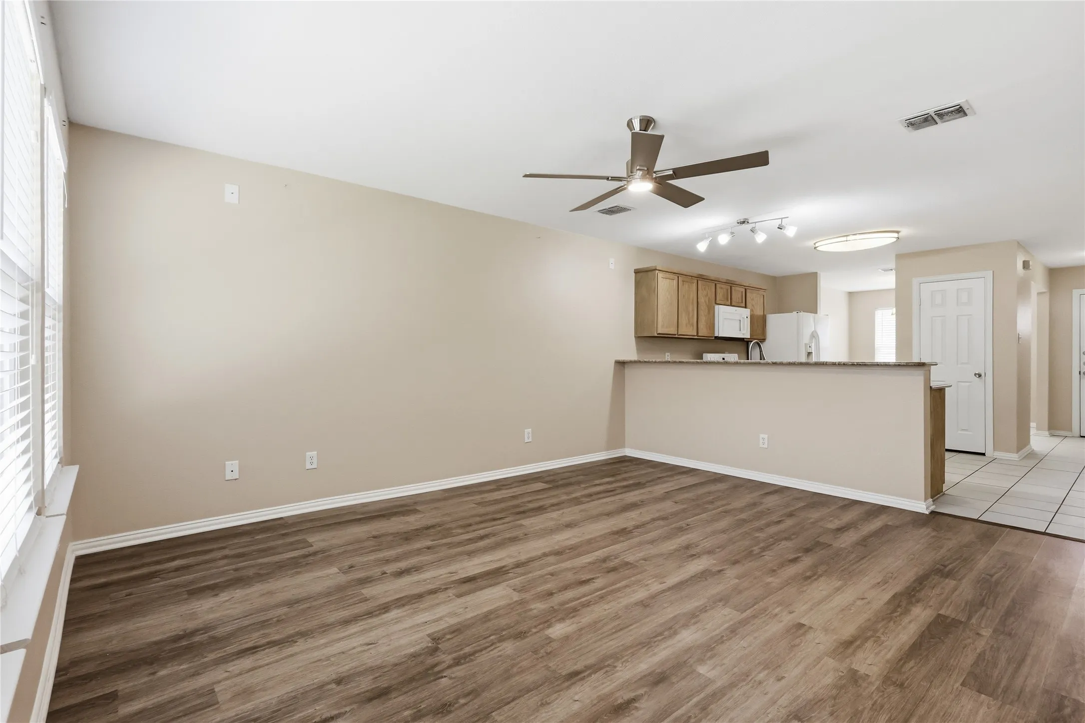 Open floor plan featuring wood-finish flooring, ceiling fan, breakfast bar, and recessed lighting