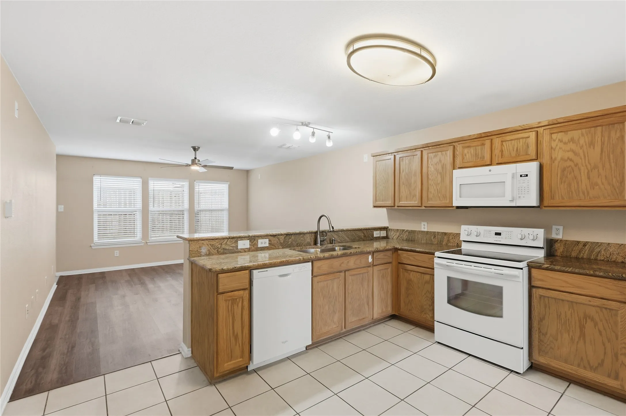 Kitchen featuring natural-finish wood cabinetry, stone-surface countertops, white built-in appliances, tile flooring, and wood-finish flooring
