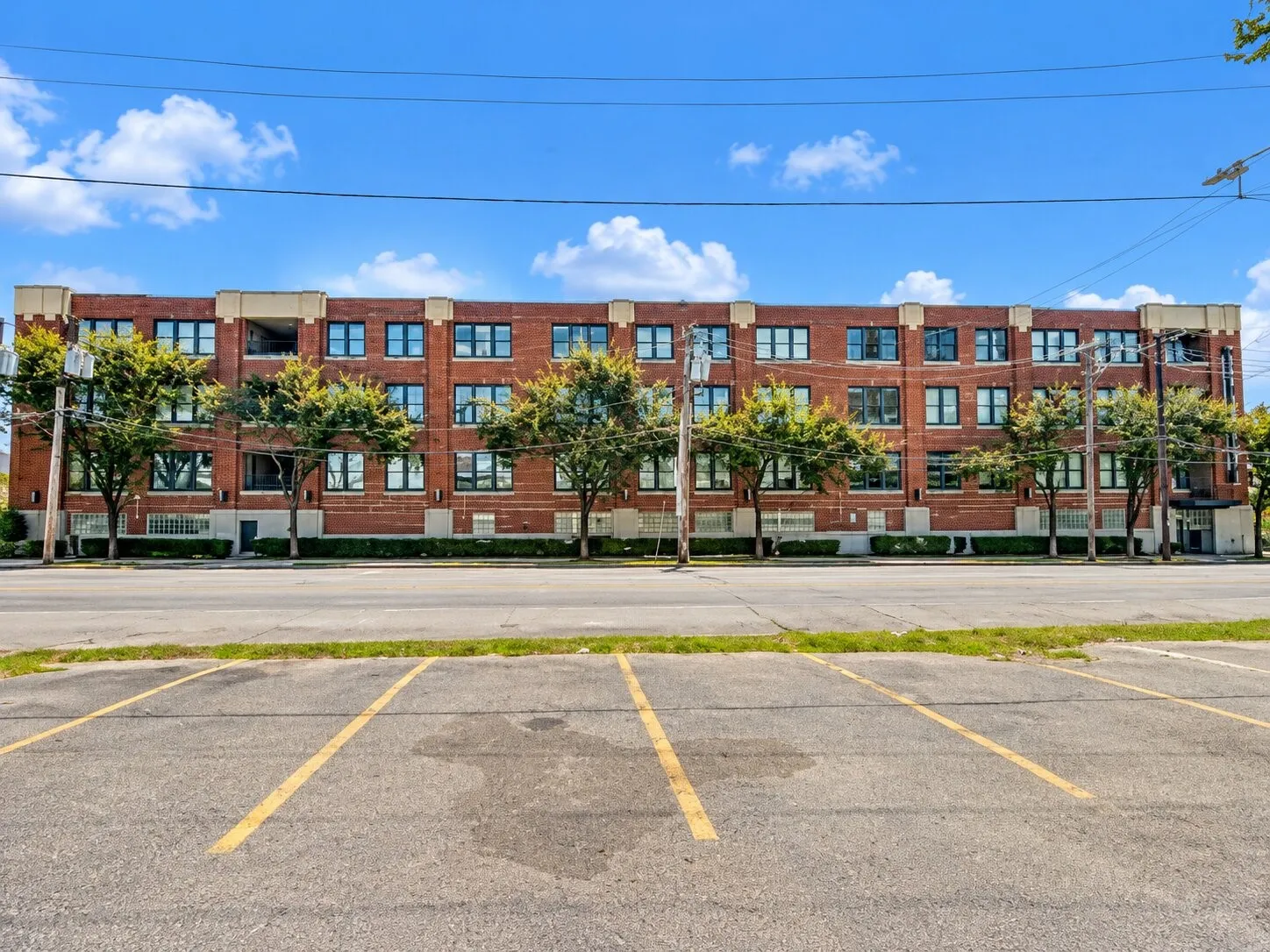 Four-story brick exterior featuring a multi-pane window grid, stone-capped roofline, and ground-level glass block accents