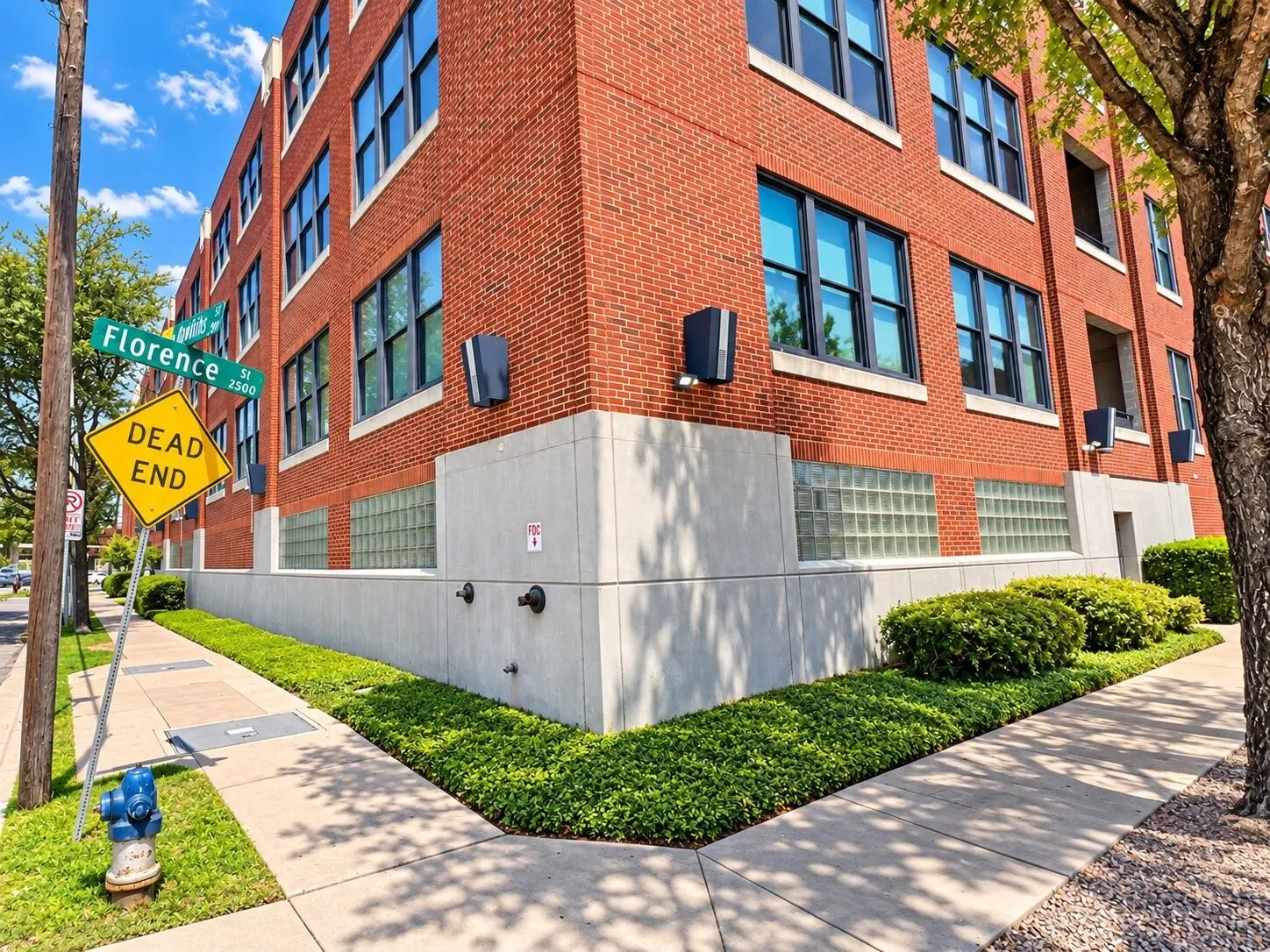 Multi-story red brick exterior featuring a concrete base, glass block masonry, and grid-pattern window groupings